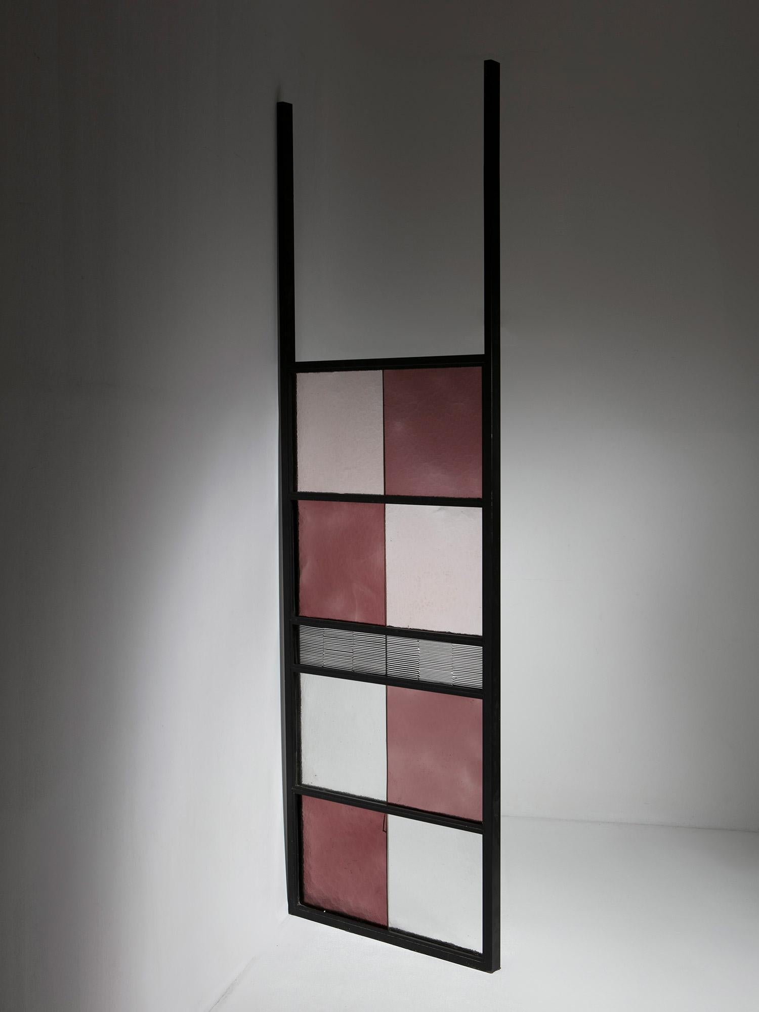 Divisorio per ambienti prodotto da Venini.
Una grande struttura in metallo nero che ospita nove piastrelle in vetro di Murano di varie dimensioni e colori.
Pezzo firmato.