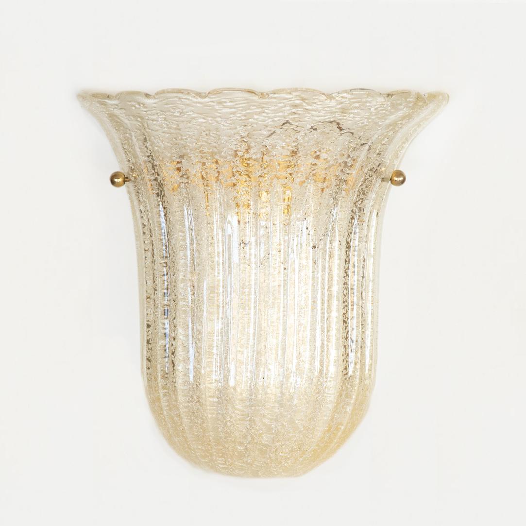 Beautiful large size Murano glass sconce from Italy, 1950's. Fluted shell shape with scalloped top edge, wavy ribbed glass and brass ball detailing. Glass has lovely gold shimmer coloring. Brass-plated metal back plate with one socket, newly rewired.