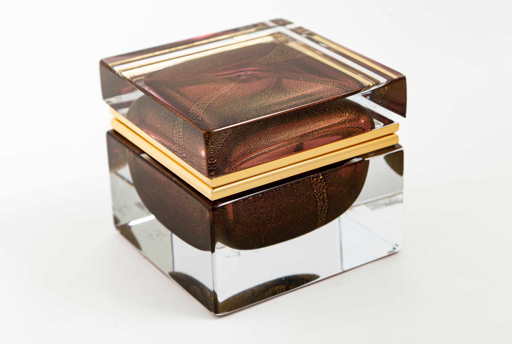 Una splendida e intramontabile scatola in vetro soffiato trasparente di Murano, realizzata a mano e di forma quadrata, con al centro un globo sommerso e infuso d'oro di colore rosa ametista, con dimensioni personalizzate per ogni scatola e finiture