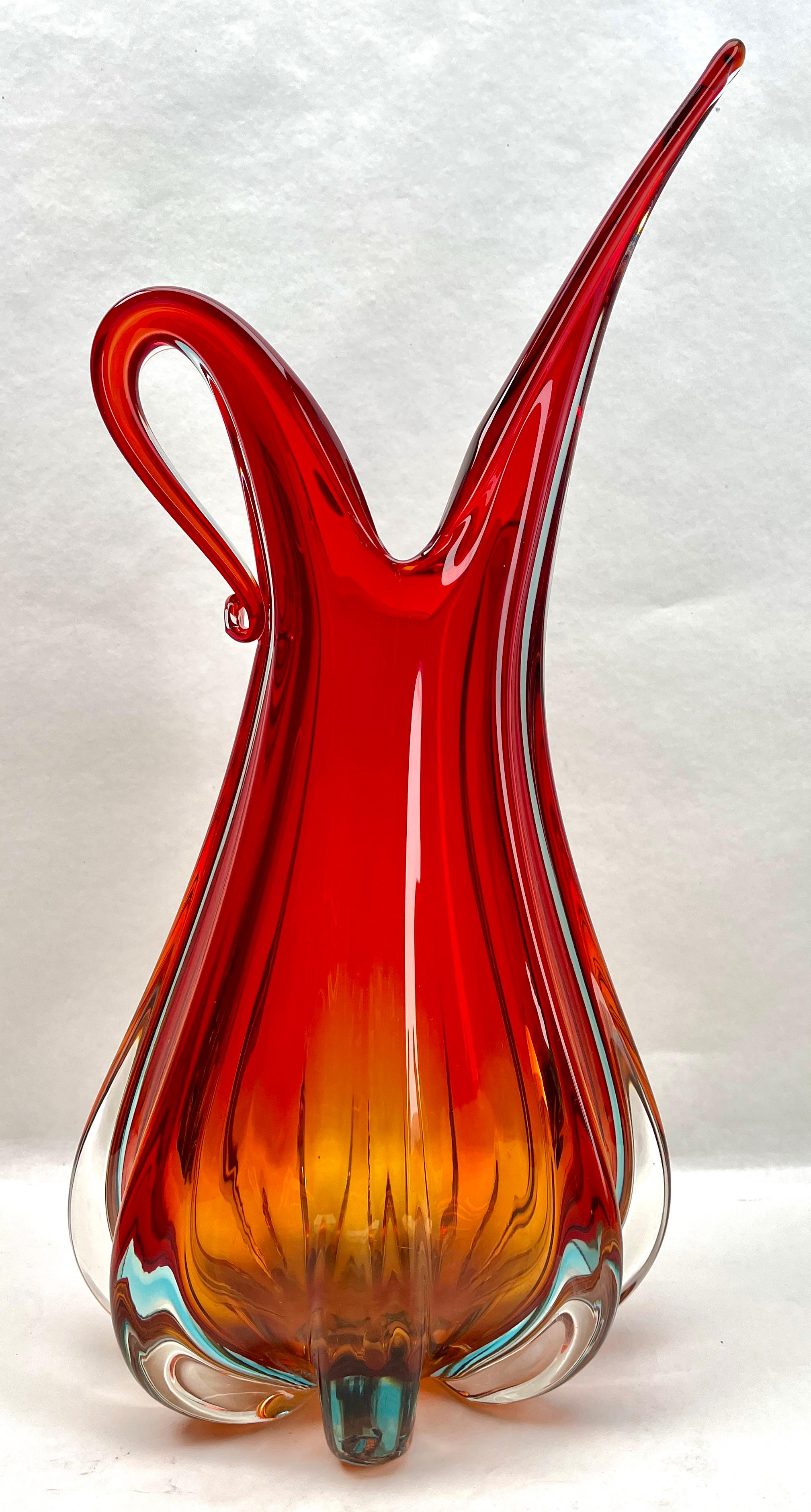 Diese gelappte Vase, die Barovier & Toso zugeschrieben wird, ist handgefertigt mit rotem Kern und Sommerso (klare Außenschicht), die sich in den klaren Glaskragen mit naturalistischer Blattform fortsetzt und Eleganz in Ihr Farbschema bringt.
Immer