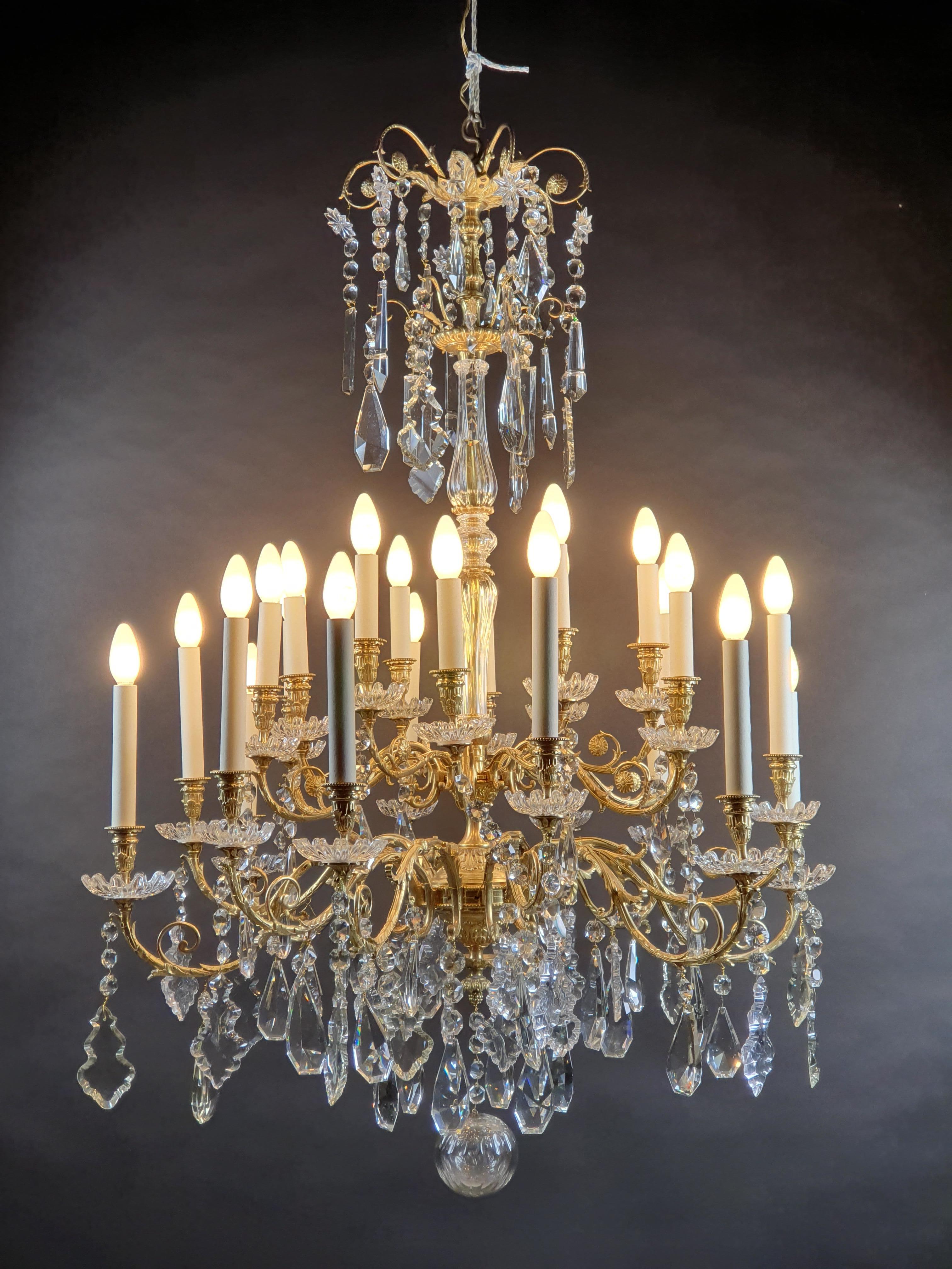 Large Napoleon III chandelier in gilded and ciseled bronze with 24 sconces in four rows, with a rich ornamentation of cut crystal pendants and toothed cups.

Quality work from the Napoleon III period around 1850.

Very good condition,