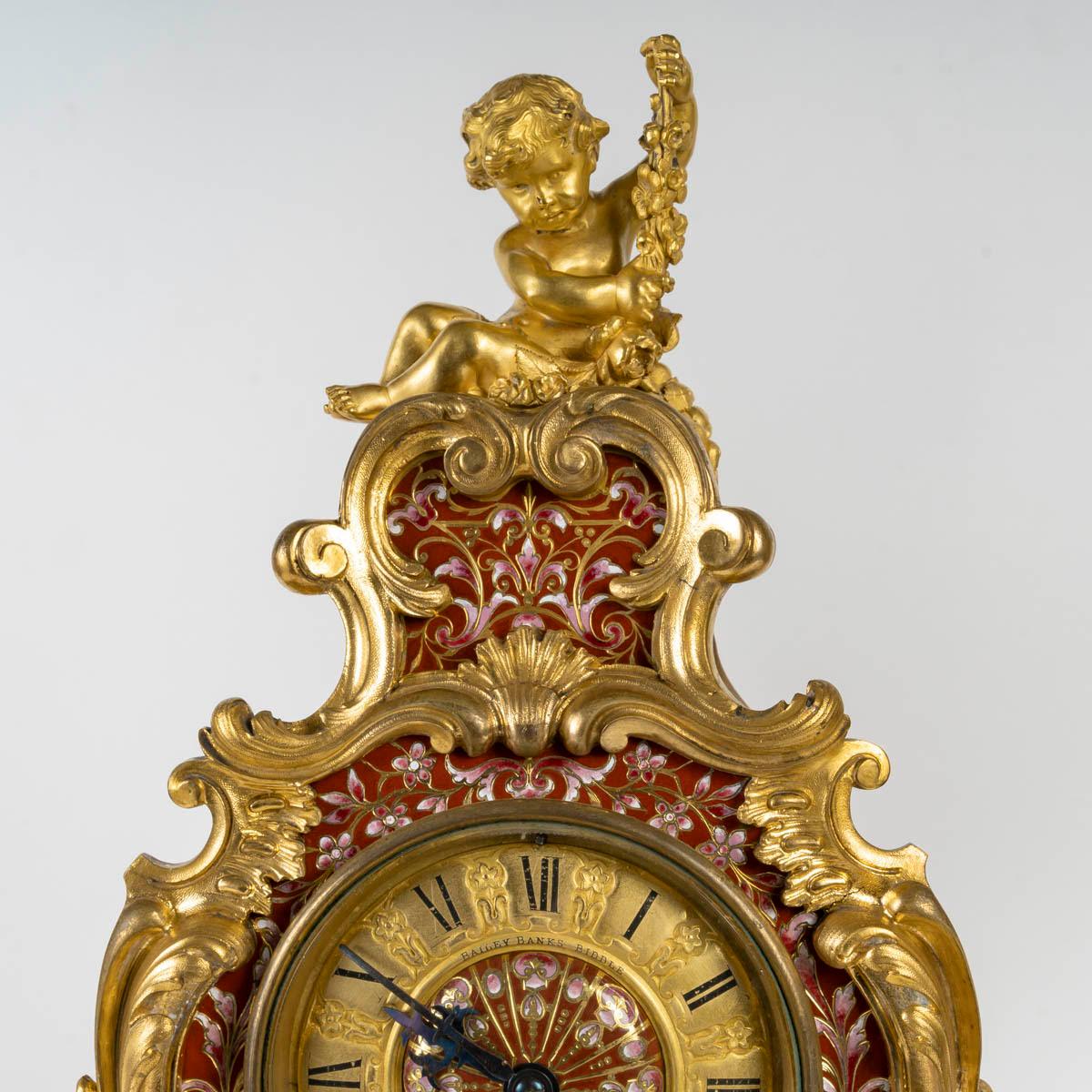 Large Napoleon III period gilt bronze mantel set, cloisonné with red and pink enamel, 19th century.

Napoleon III period mantel set, 19th century, in gilt bronze, cloisonné with red and pink enamel, clock and two candelabras.
Clock: H: 47.5cm, W: