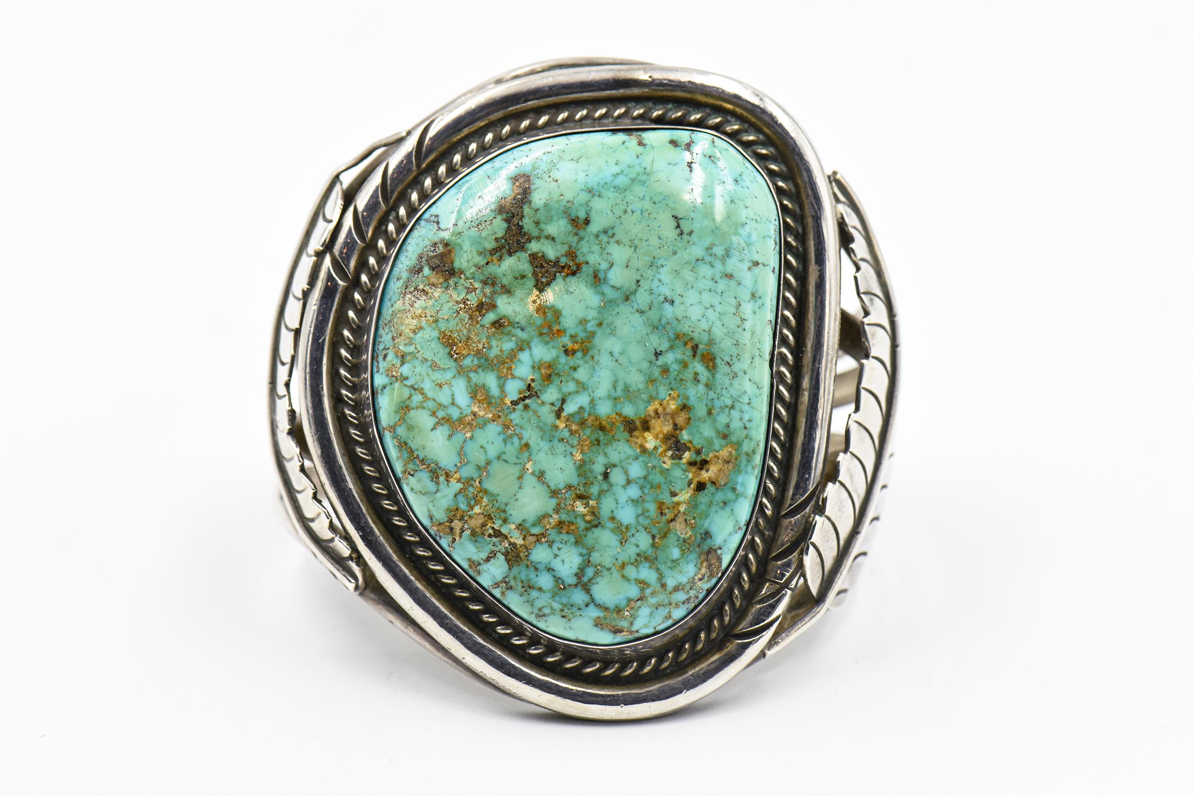 Stunning Native American sterling silver cuff bracelet featuring a bezel set large turquoise with a rope frame.  On either side of the turquoise is an applied silver leaf.
 Interior circumference  6.5