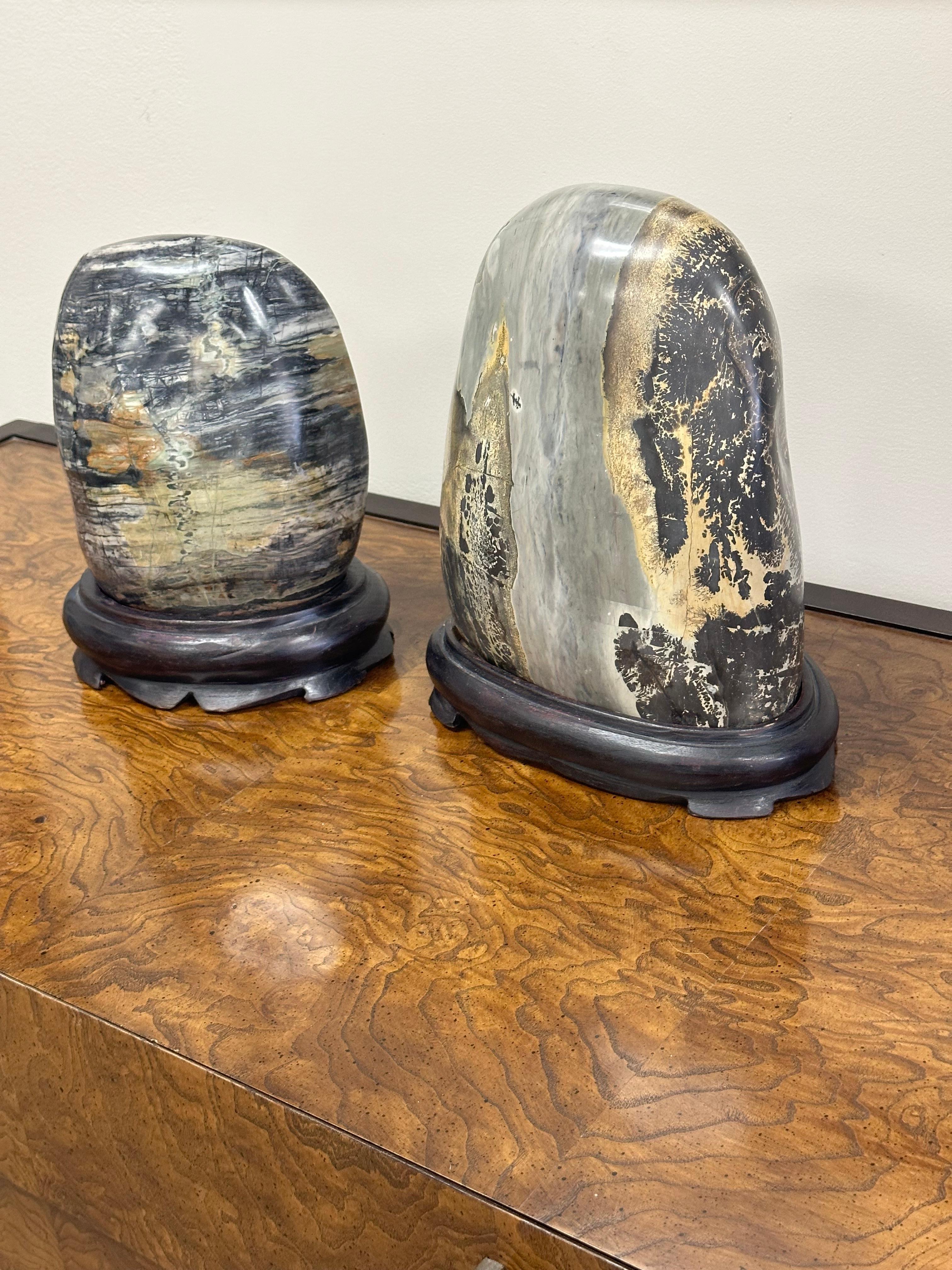 Large Natural Marble Stone Sculptures on Carved Wooden Stands, a pair

A set of two large, polished natural marble stones, displayed on custom carved wooden stands. These are sculptural, organic pieces, with varying colors and movement within the