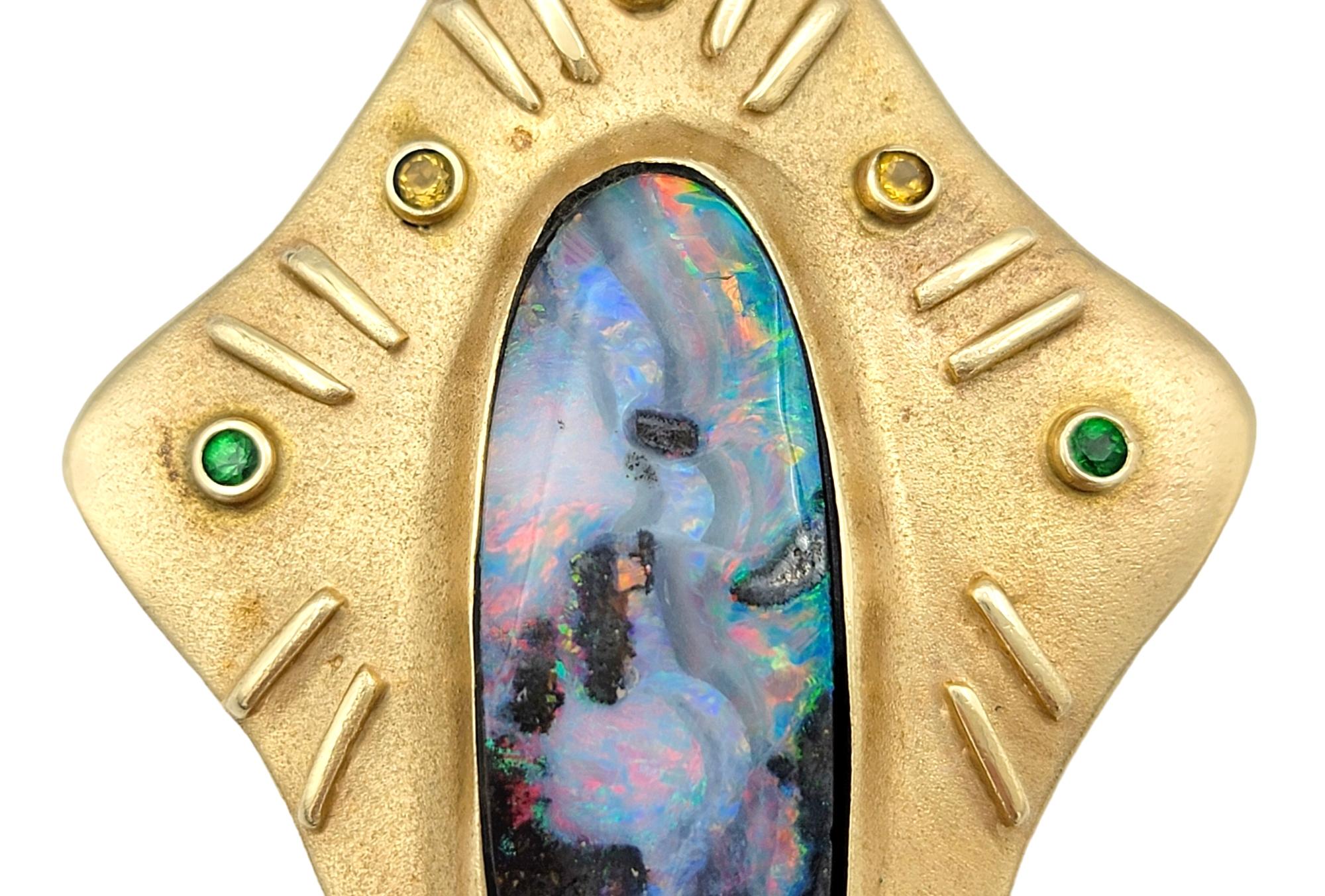 Ce superbe pendentif avec opale naturelle et pierres précieuses multicolores cultivées en laboratoire rayonne dans sa monture en or jaune brossé 14 carats. Ce pendentif allongé unique est un mélange harmonieux de couleurs et de textures vibrantes,