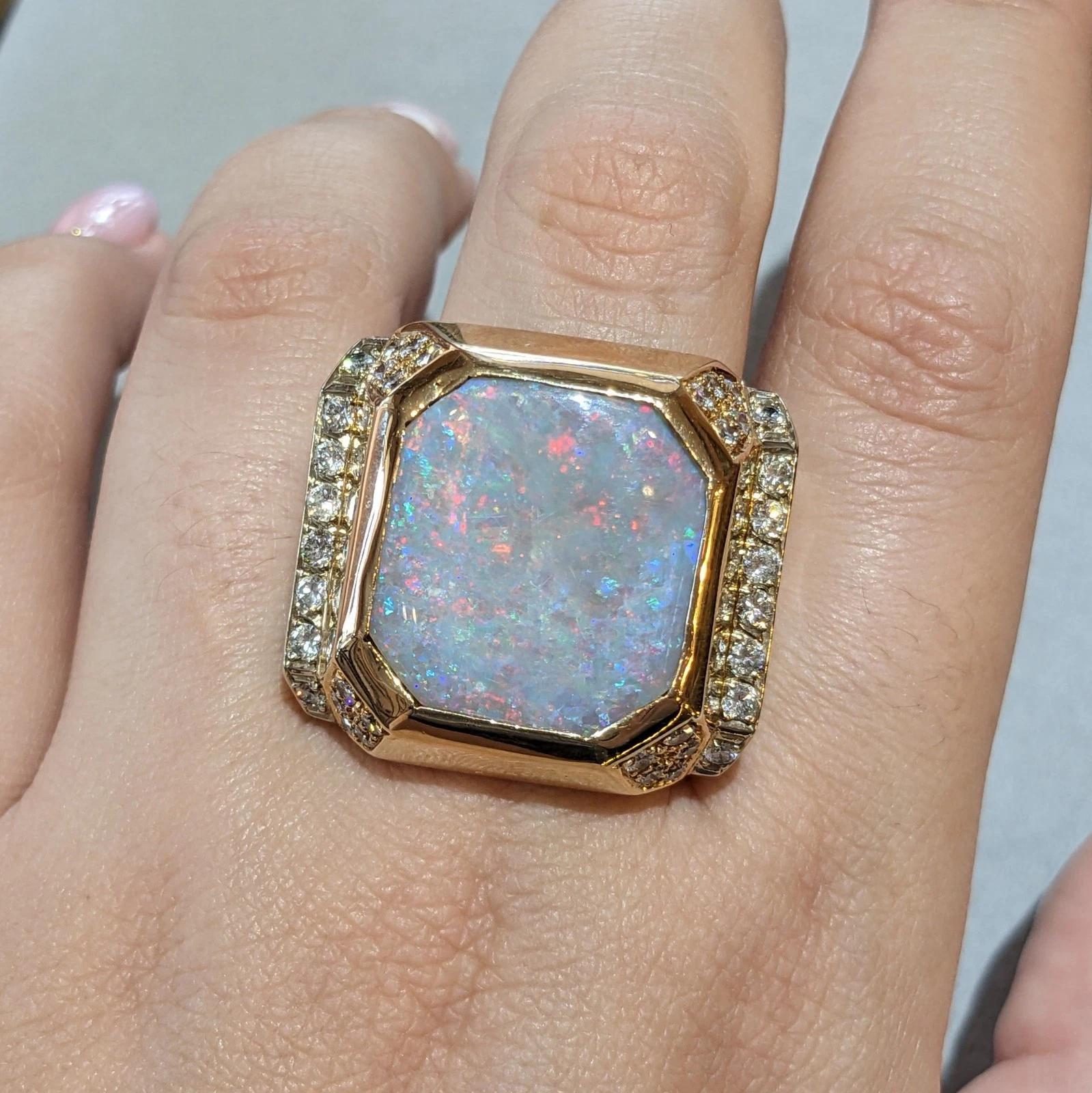 Natural Opal Ring with Diamonds in 14k Yellow Gold 

Natural Opal Ring with Diamonds features a Square Shaped Opal with Beveled edges with Red, Orange, Blue, Green, and Purple Play-of-Color on grey background Bezel set in 14k Yellow Gold setting