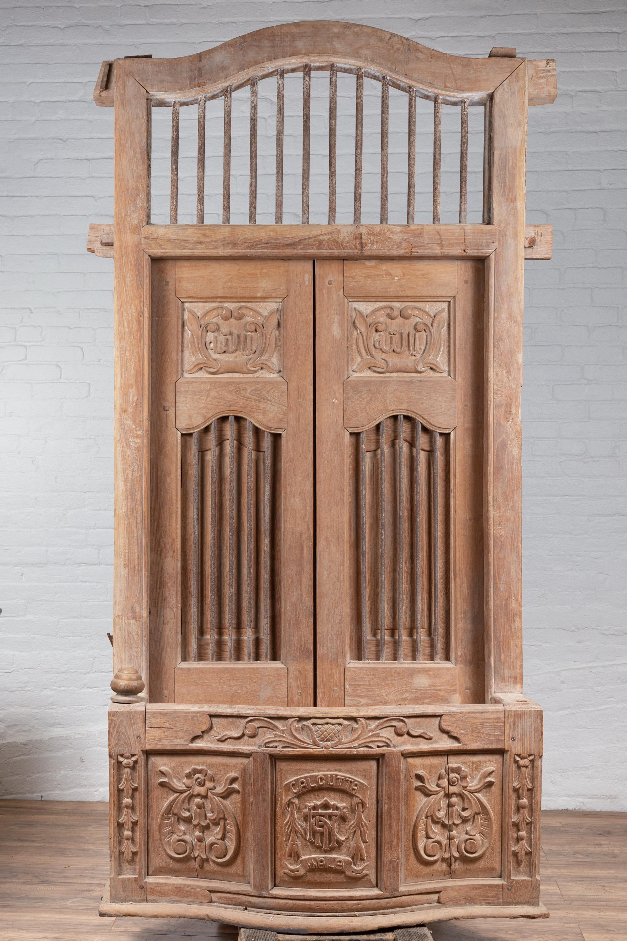A large Indian hand carved wooden bonnet top window balcony from the early 20th century with rod motifs, calligraphy and foliage. Found in India, this window balcony captivates our attention with its large proportions and natural finish. Adorned