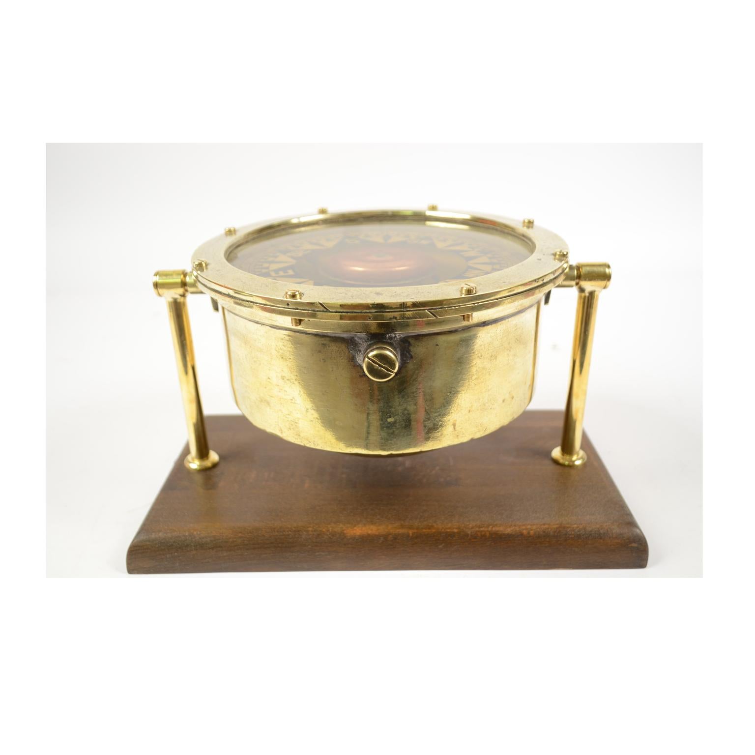 Large nautical liquid compass, brass, on universal joint, British manufacture of the second half of the 19th century mounted on wooden board. The compass has a cylindrical brass container, on the bottom of which a stem of hard metal is fixed, on