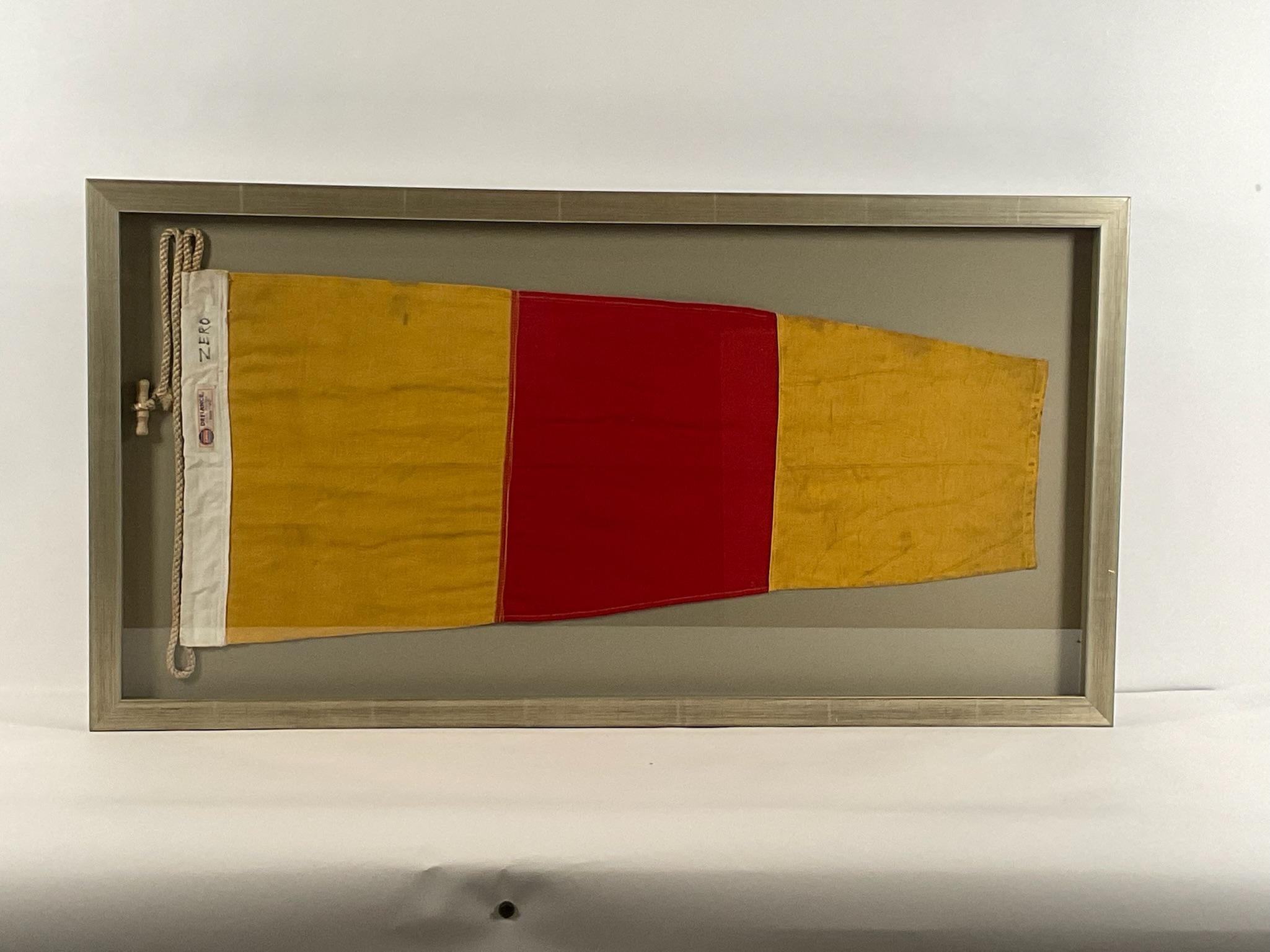 Framed linen signal flag fitted to a shadow box frame. This nautical flag represents the numeral ZERO. With makers label from Annin Flag Company. Stitched in panels of yellow and red. Heavy canvas hoist with rope and toggle.

Weight: 13 lbs.
Overall