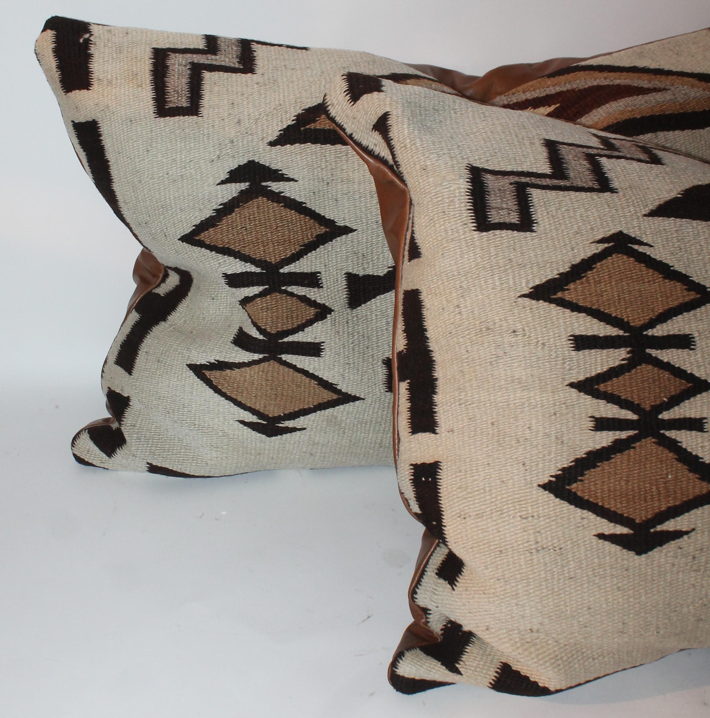 These large Navajo Indian weaving big bolster pillows have leather backings and down and feather fill. The condition is very good.