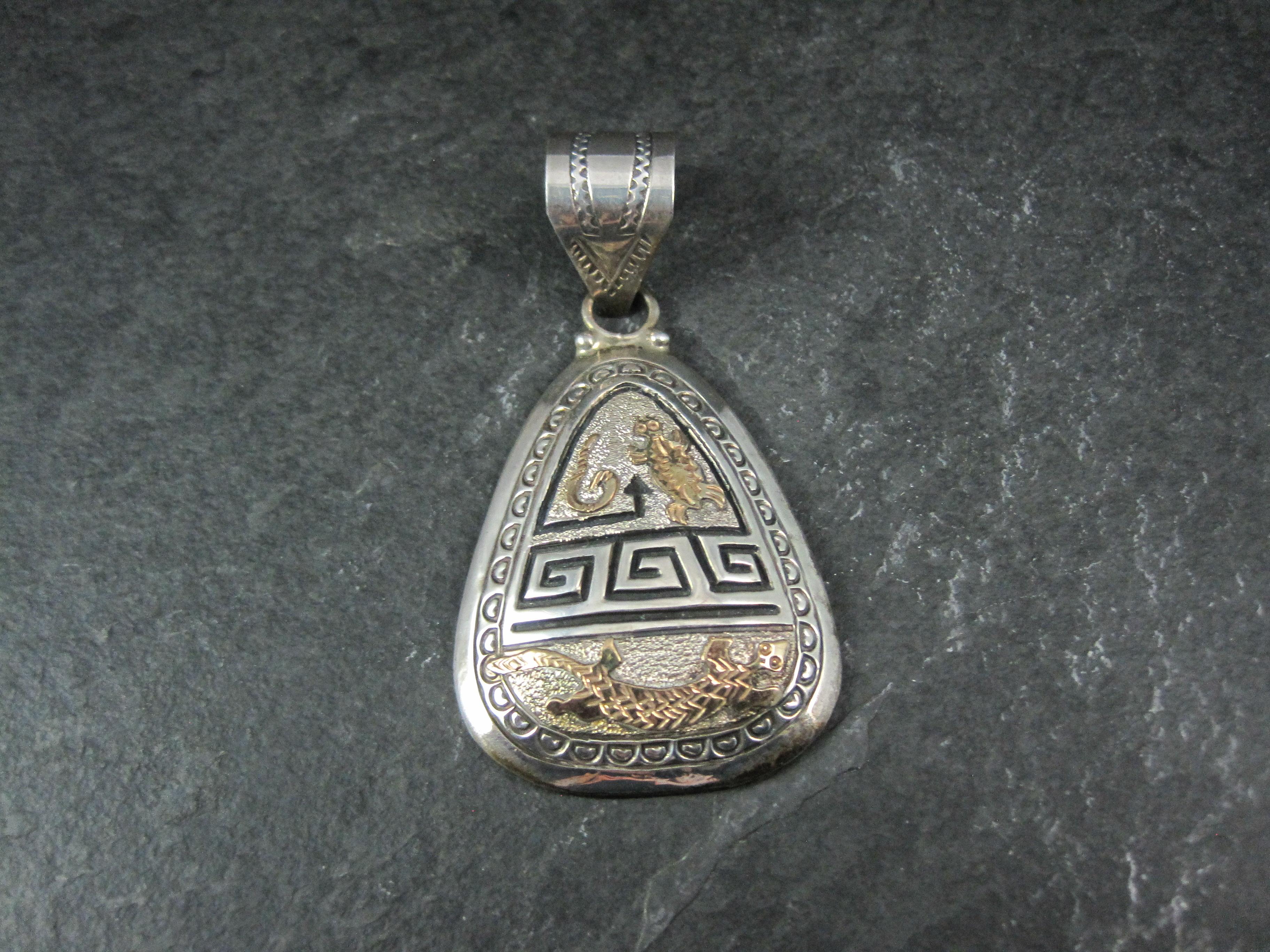 Questo splendido ciondolo è opera dell'argentiere Navajo Alonzo Mariano.
È in argento sterling con lucertola, tartaruga e serpente sovrapposti in oro 12 carati. 
Questo ciondolo misura 1 1/2 per 2 7/8 pollici, incluso il fermaglio.
La cauzione può