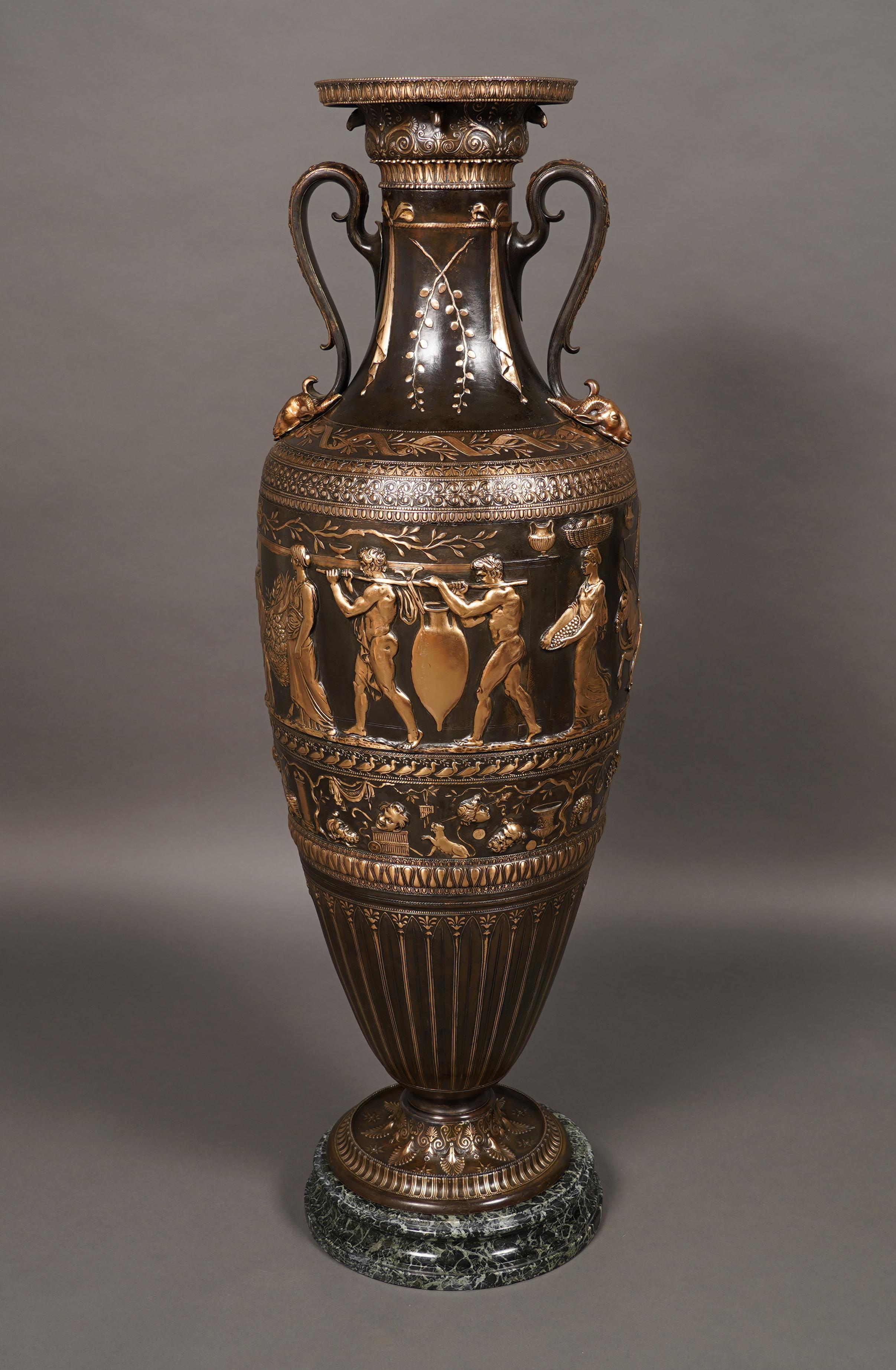 Important vase néo-grec en forme d'Amphora, réalisé en bronze à deux patines. Le corps est décoré d'une riche frise continue en bas-relief présentant une procession de personnages portant leurs offrandes au temple, soulignée par un décor de masques