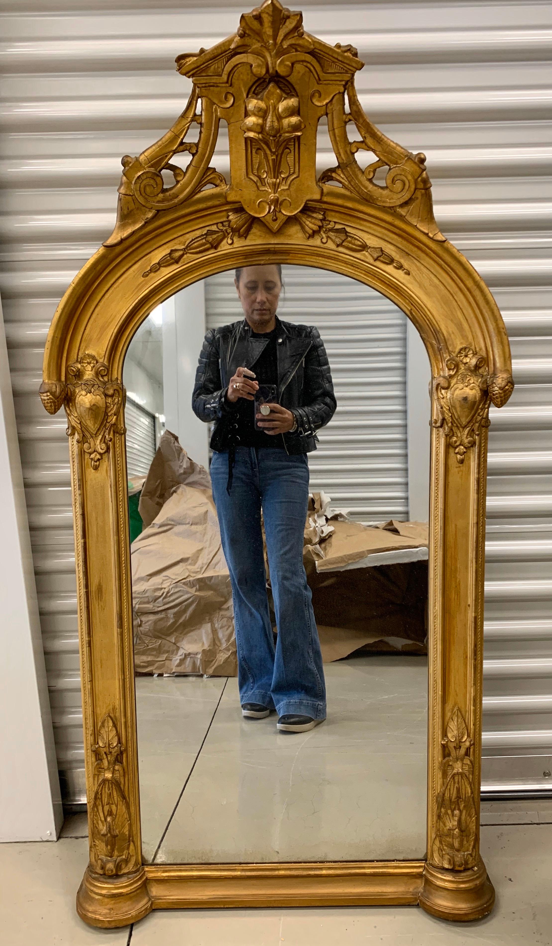 Stunning neoclassical antique mirror that will sit on a mantel or hang on wall, your choice. What makes this antique mirror truly special is the carved giltwood finial that bows out at top. There are some areas of chipping and cracking in the