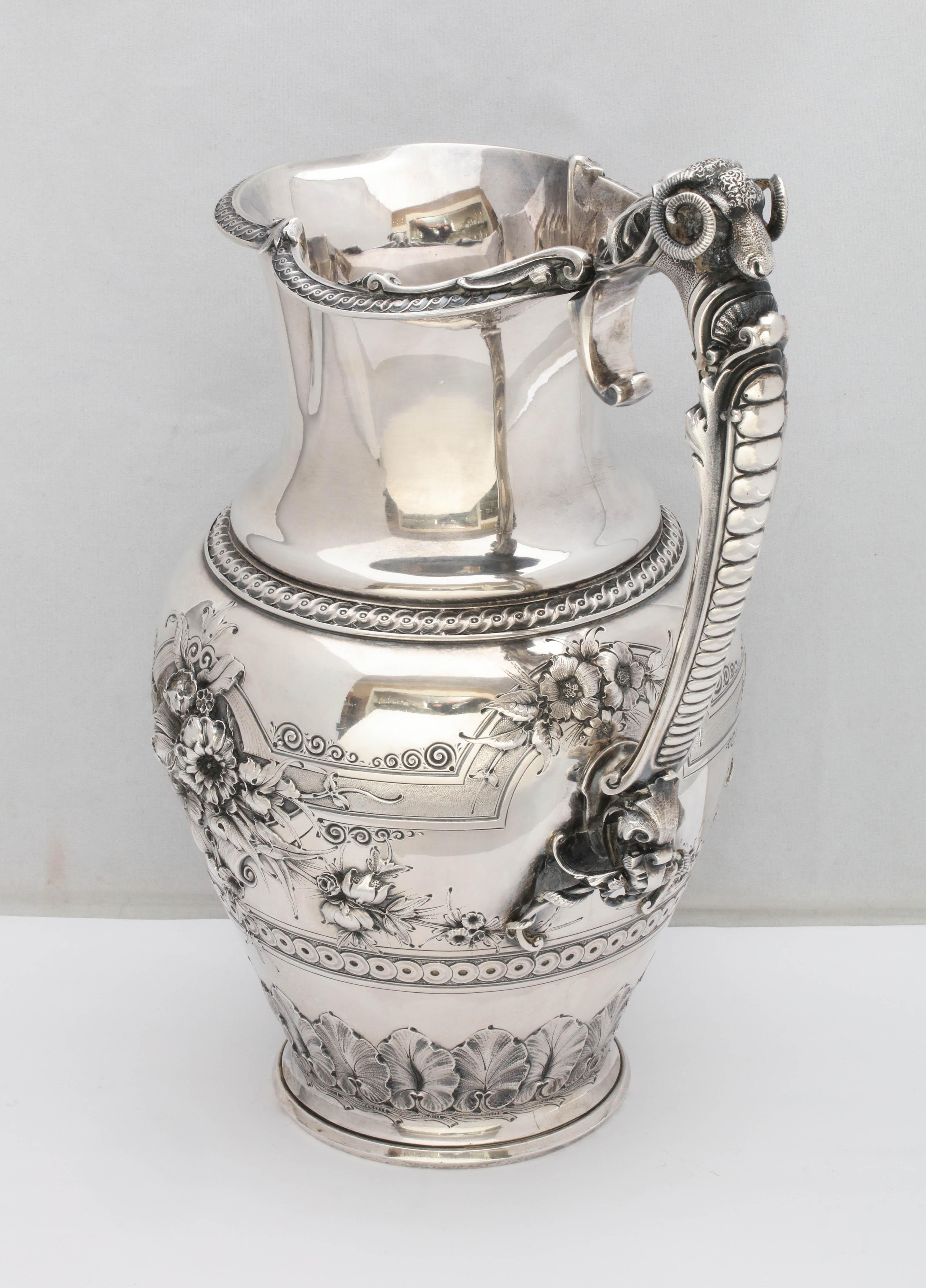 Large, neoclassical, Coin Silver pitcher by Gorham Manufacturing Co., Providence Rhode Island, circa 1860. Decorated with flowers and leaves, and having a ram's head at the top of the handle. Rim of opening is gracefully scalloped. Measures 12 3/4