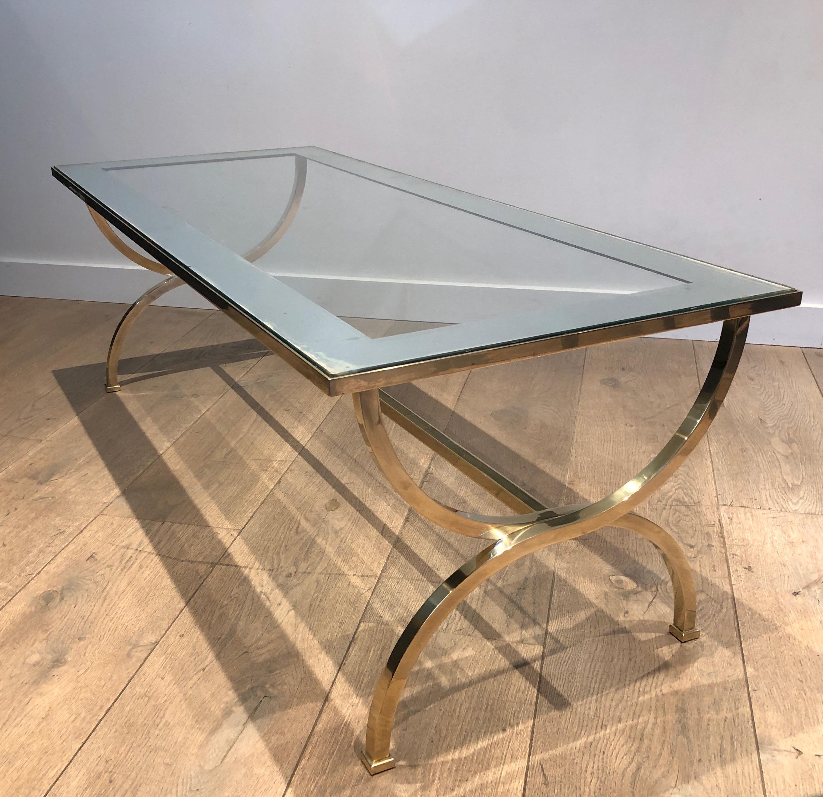 This large neoclassical style coffee table is made of brass with a glass top surrounded by a large silver line. This is a French work attributed to Maison Jansen. Circa 1940.