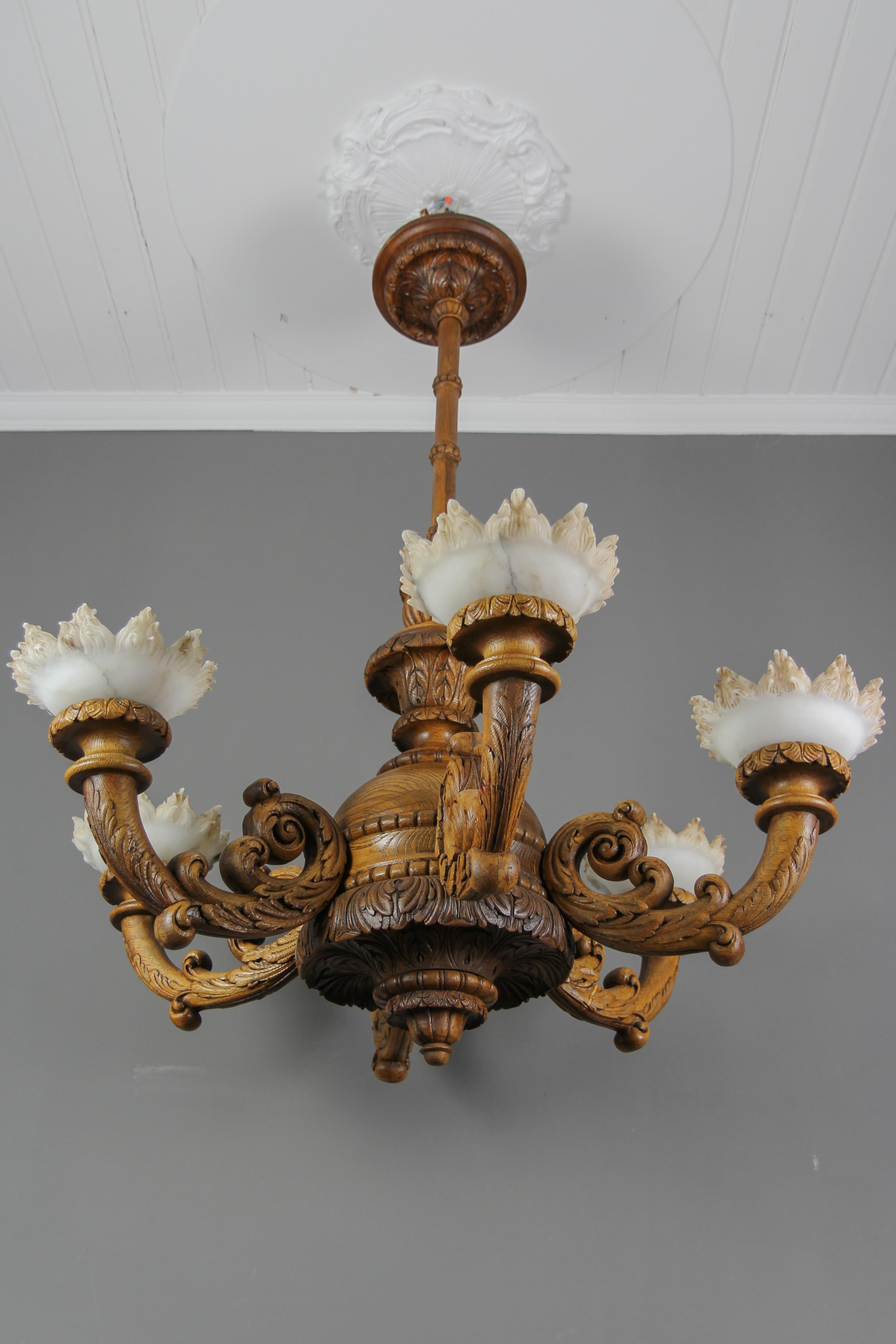 Large Neoclassical Style Carved Oakwood and Alabaster Chandelier, Germany, circa the 1920s.
This impressive Neoclassical style chandelier in oak is finely hand-crafted, made in the first third of the 20th Century.  
Impeccable details of carved