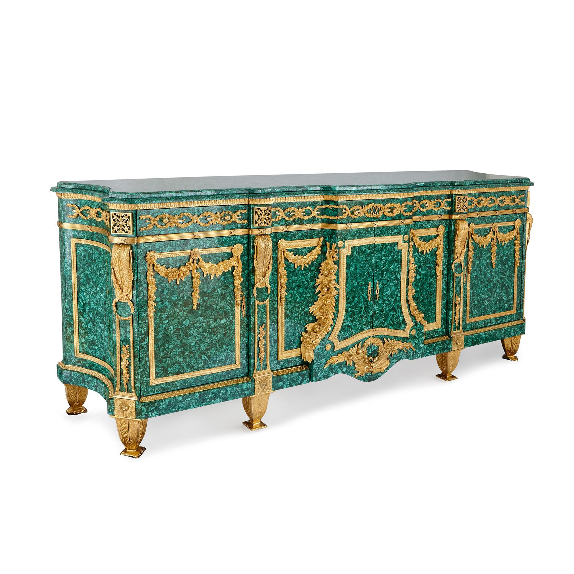 This fine and very large side cabinet is lavish in both design and materials, featuring a bright green malachite gemstone veneer (a later addition) and lustrous gilt bronze mounts. The cabinet is of rectangular shape, being very wide and