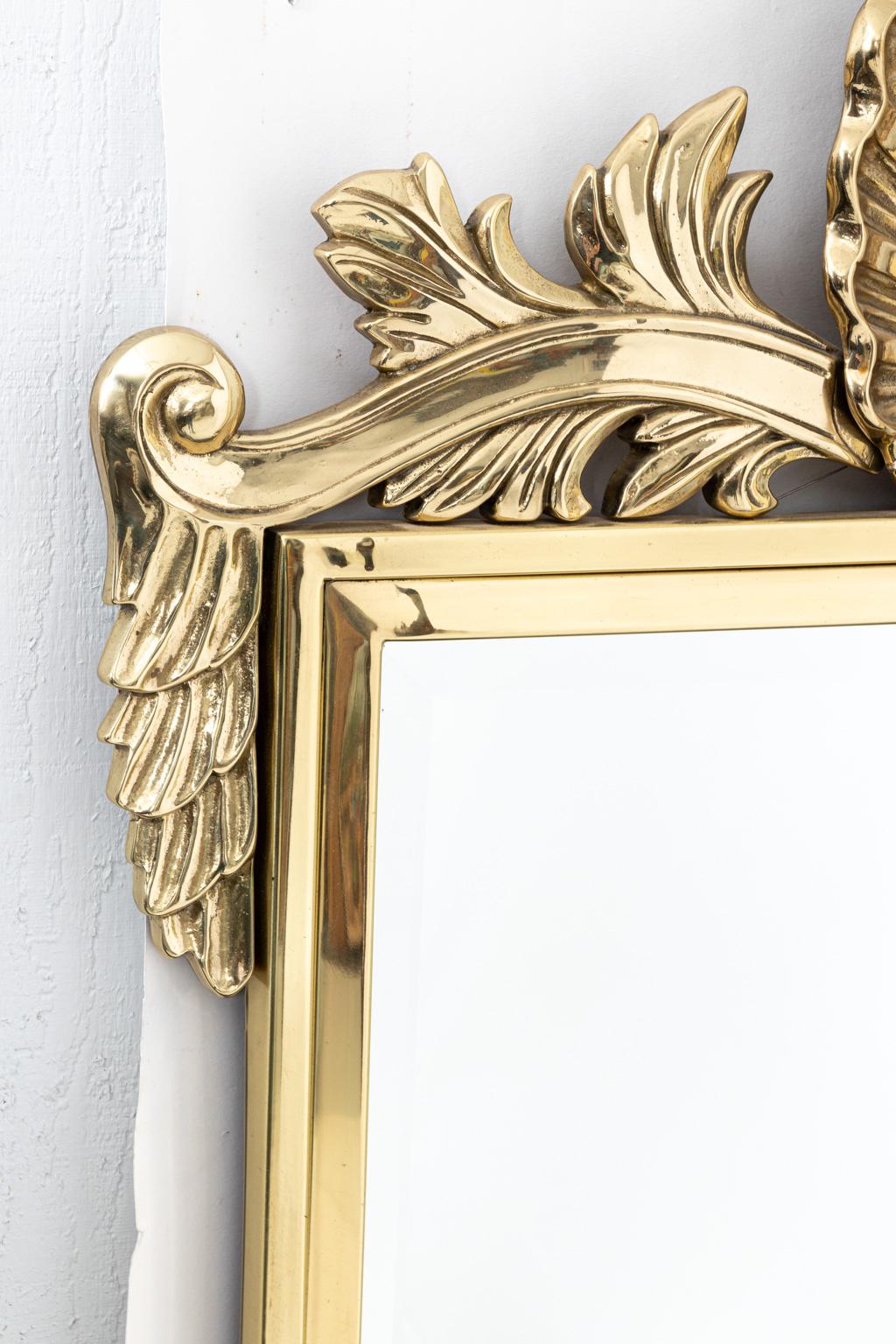 Large solid brass mirror with scallop shell crest featuring scroll and foliate decoration, circa 1970s. The stepped frame also features a beveled mirror. Please note of wear consistent with age. Made in the United States.