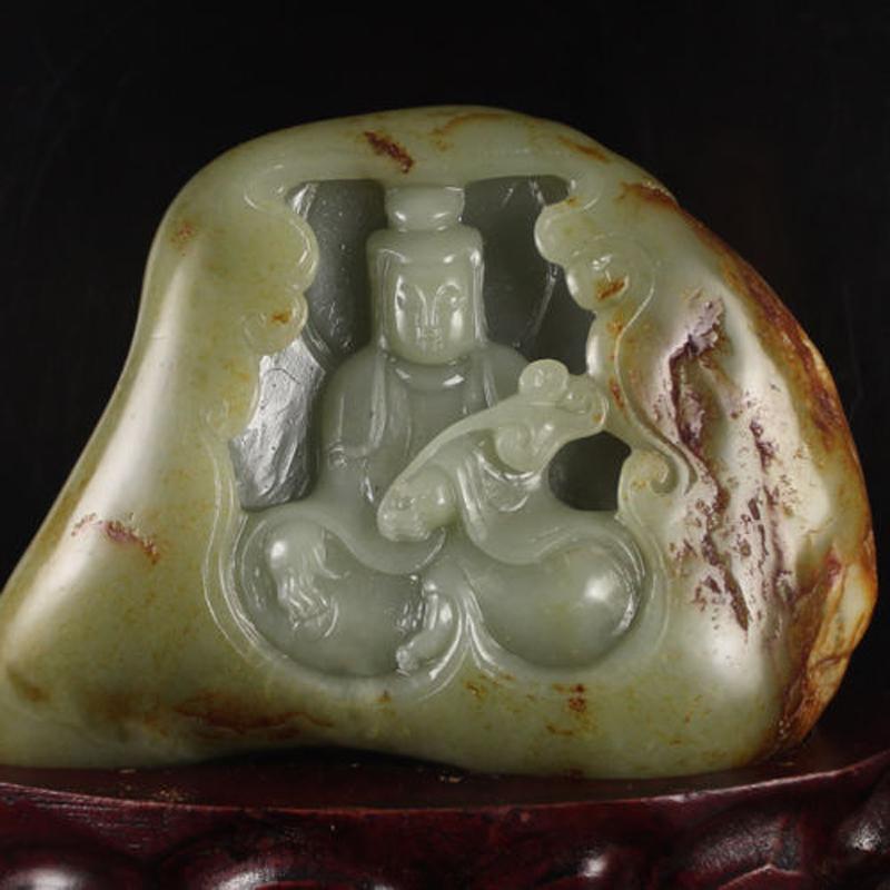 This is a beautiful, hand-carved nephrite jade sculpture in perfect condition. It depicts Kwan Yin, the Goddess of Great Compassion sitting within an alcove of a rock. Holding a ruyi scepter in her hand, she is peaceful and in a state of serenity.