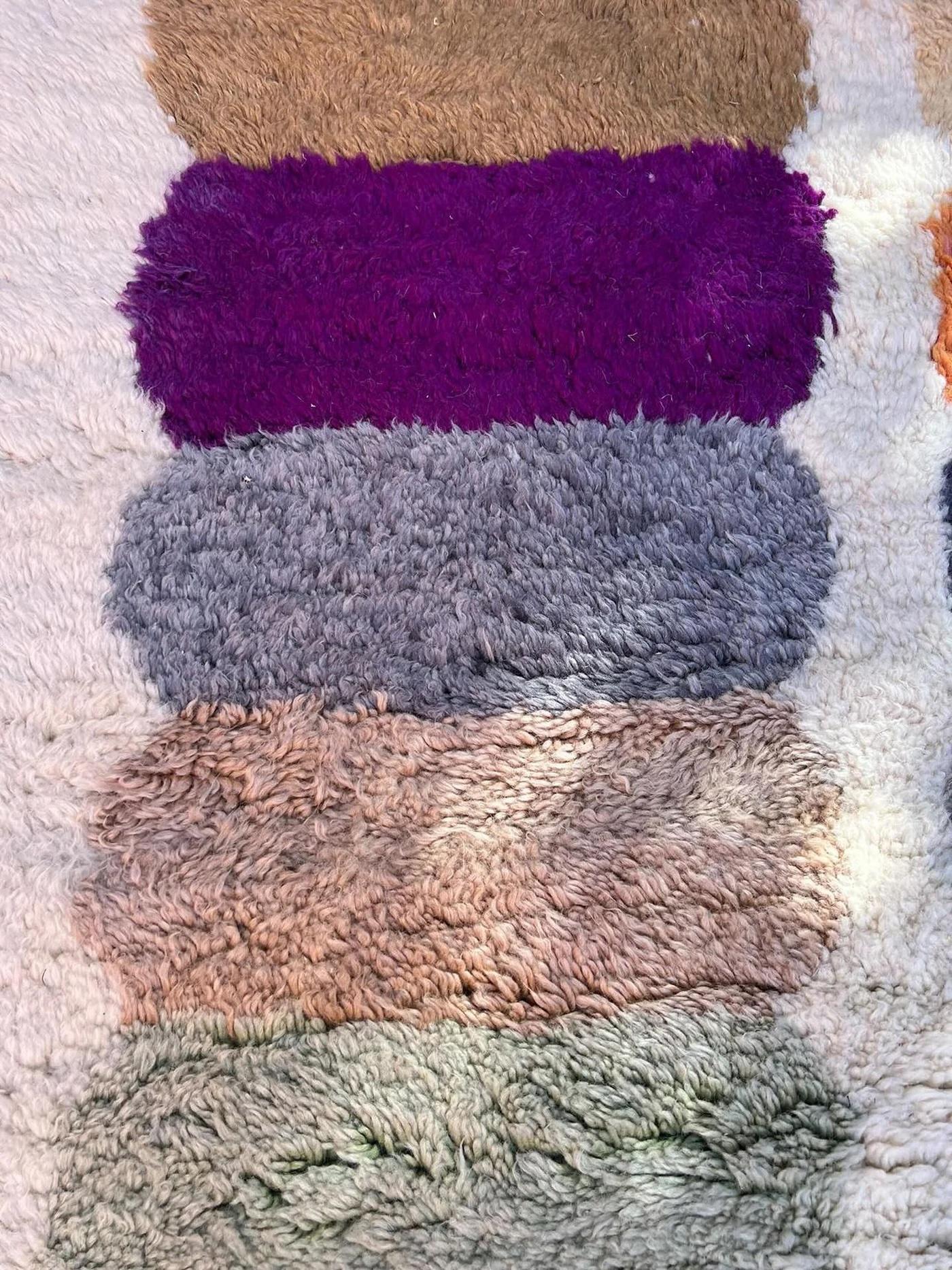 This large, modern handwoven Moroccan rug was made by hand by skilled artisans in the Atlas Mountains. It features a high quality, neutral cream wool base with a multi-colored abstract line design, forming irregular stripes in the most pleasant