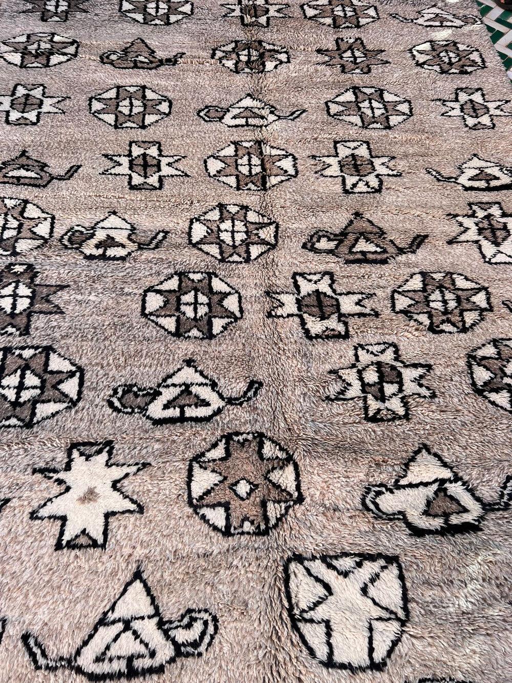 Esta gran alfombra marroquí de color topo fue confeccionada a mano por hábiles tejedores en la cordillera del Atlas utilizando la lana M'Rirt más suave y de mayor calidad.  Una base neutra de color marrón jaspeado forma el fondo de un diseño