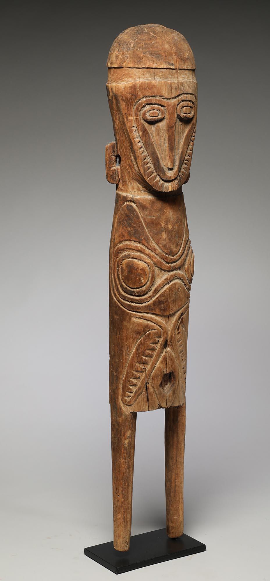 Large carved light wood standing stylized figure with geometric face, second face in body with wild arms. Projecting rectangular ears. Carved 
