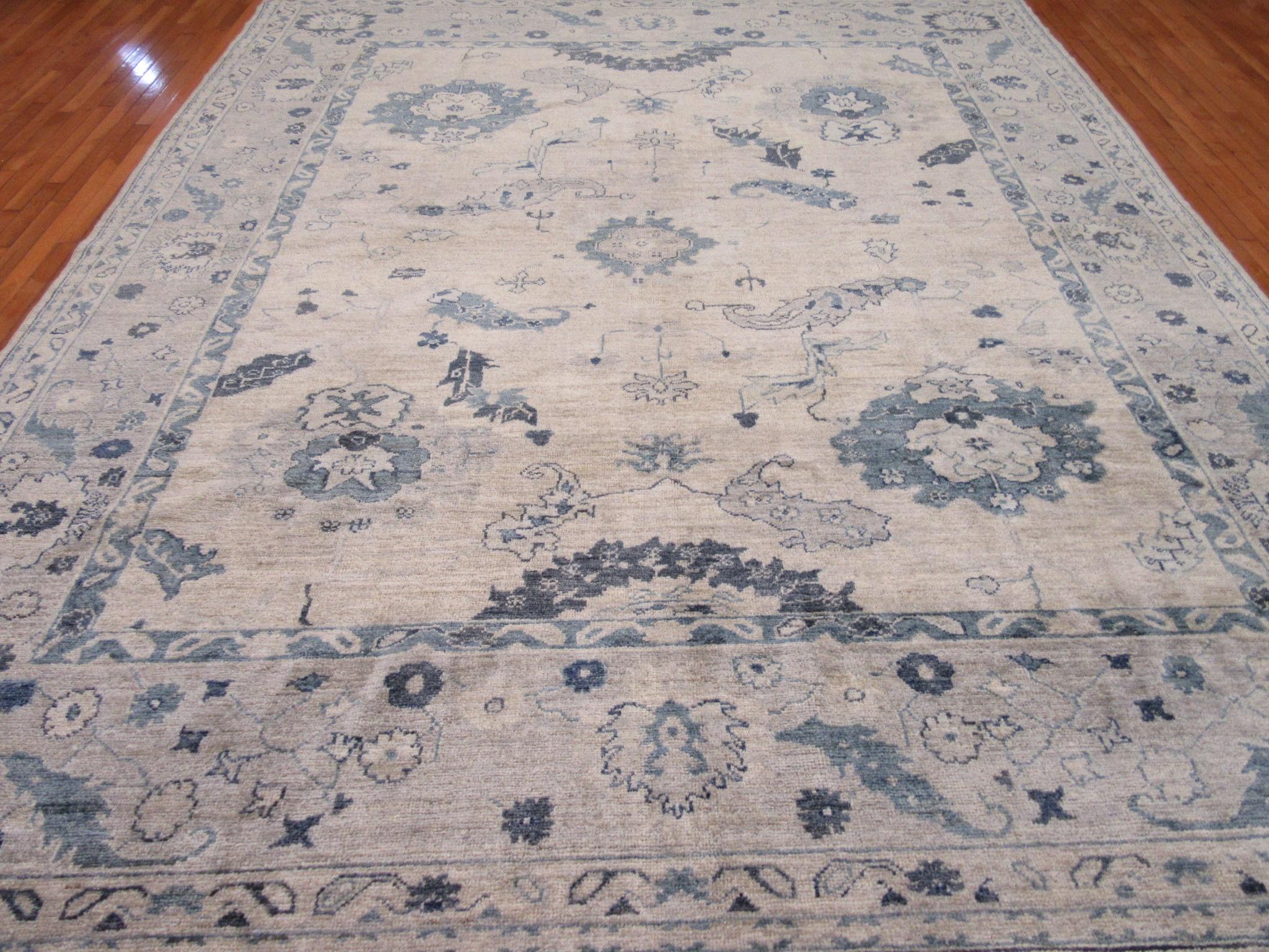 This is a new hand-knotted Oushak rug from Turkey. It is made with all Fine Turkish wool in a large-scale all-over pattern. Only few colors ivory , gray and blue have been used to create a mellow cool patina. The rug measures 10' 4'' x 13' an ideal