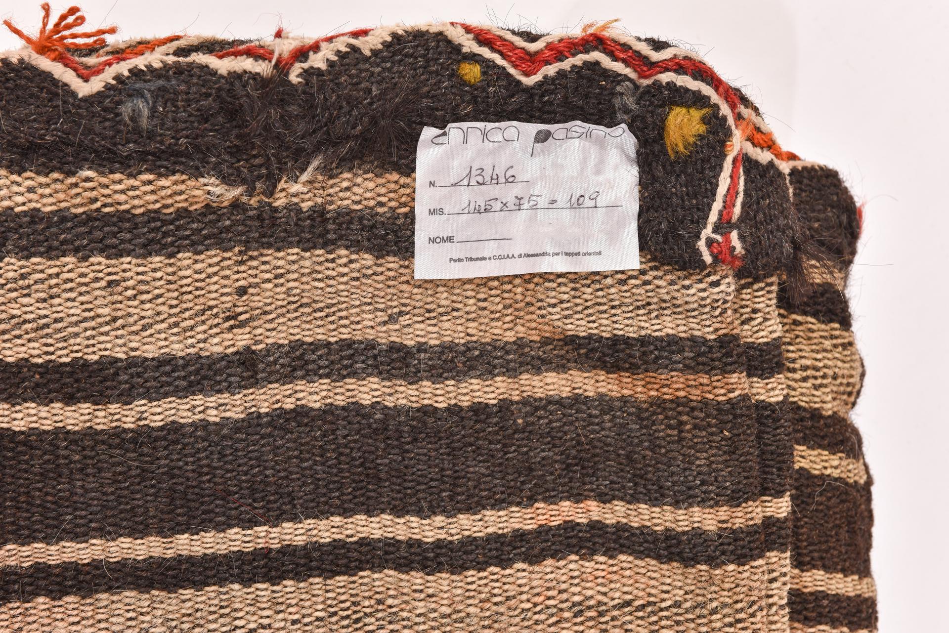 Gran alforja nómada, muy rústica e interesante. Está tejida sólo con lanas crudas y negras, pero alegrada con mechones de lana multicolor.
Insertando dos cojines se convierte en un cómodo asiento, también como respaldo.
Tiene algunos agujeros en la