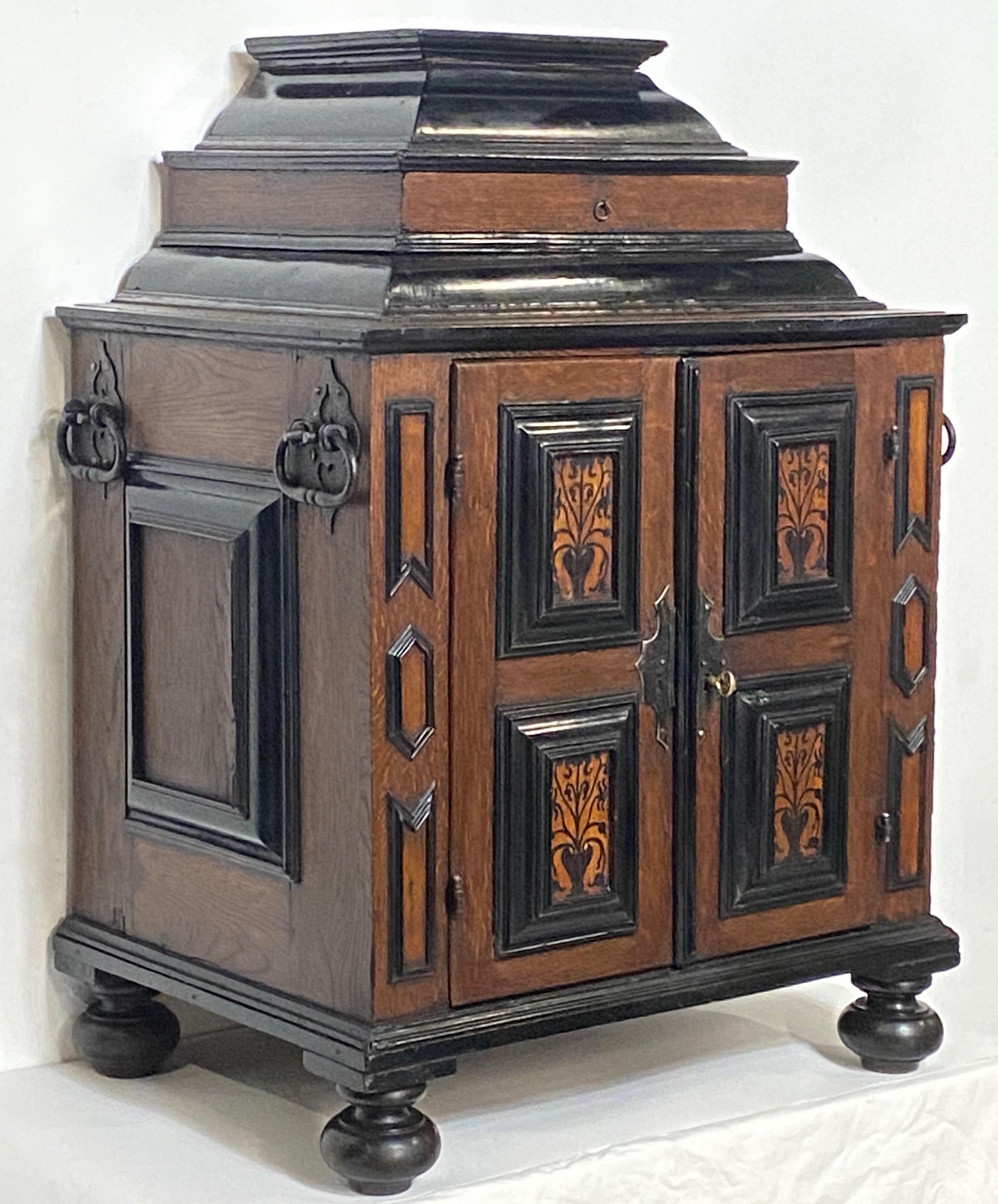 Large and unique jewelry or collectors cabinet.
Oak and Blackened Walnut with inlay marquetry detail, having original iron hardware and original lock (no key). Fitted multi drawer interior, and the top of the cabinet opening to reveal a red fabric