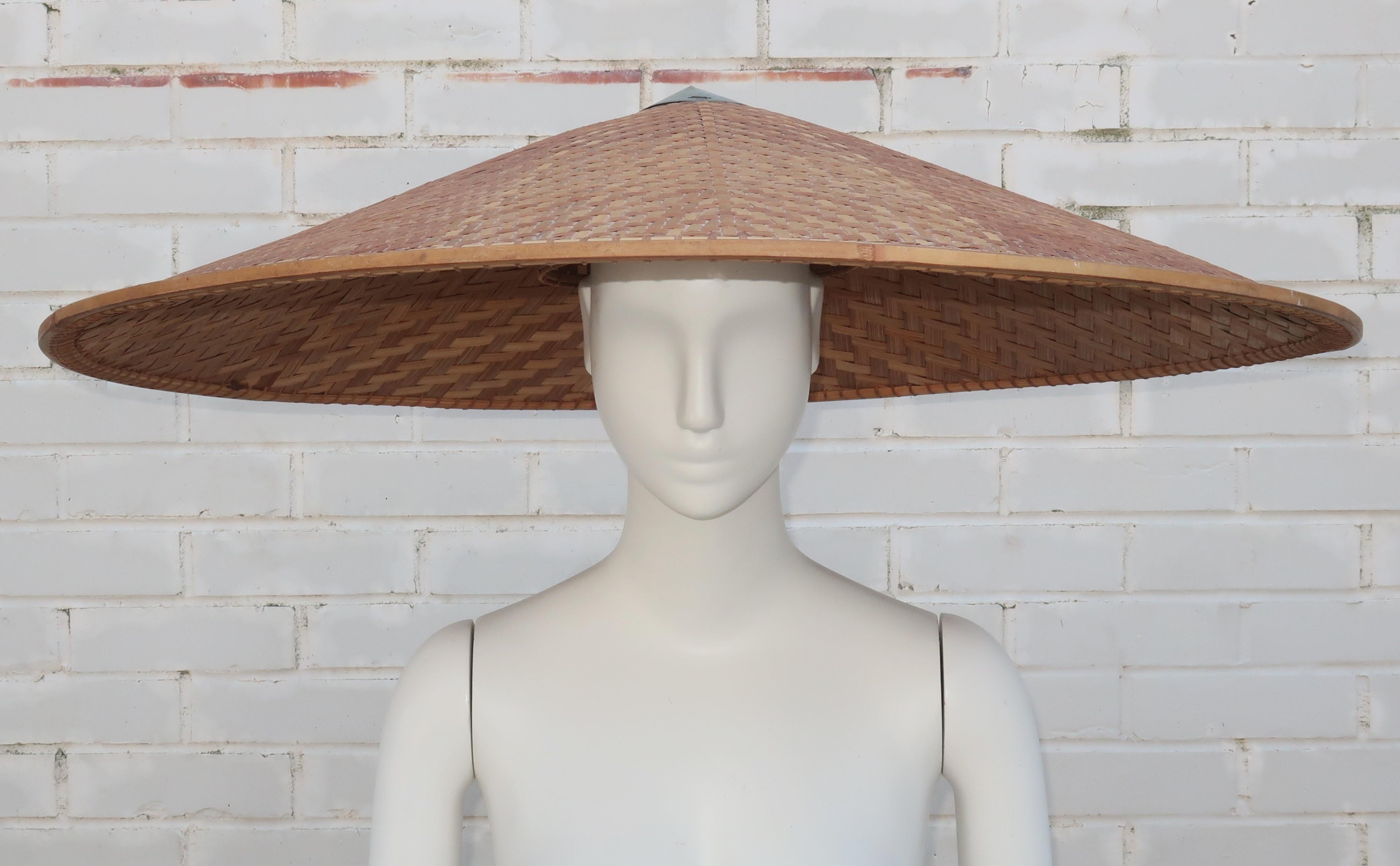 Qui a besoin d'un parapluie quand on a ce fabuleux chapeau ?  Il s'agit d'un très grand chapeau des années 1950 en osier tressé avec un bord en bambou et en paille et une calotte en métal.  L'intérieur est équipé d'une bande en treillis qui