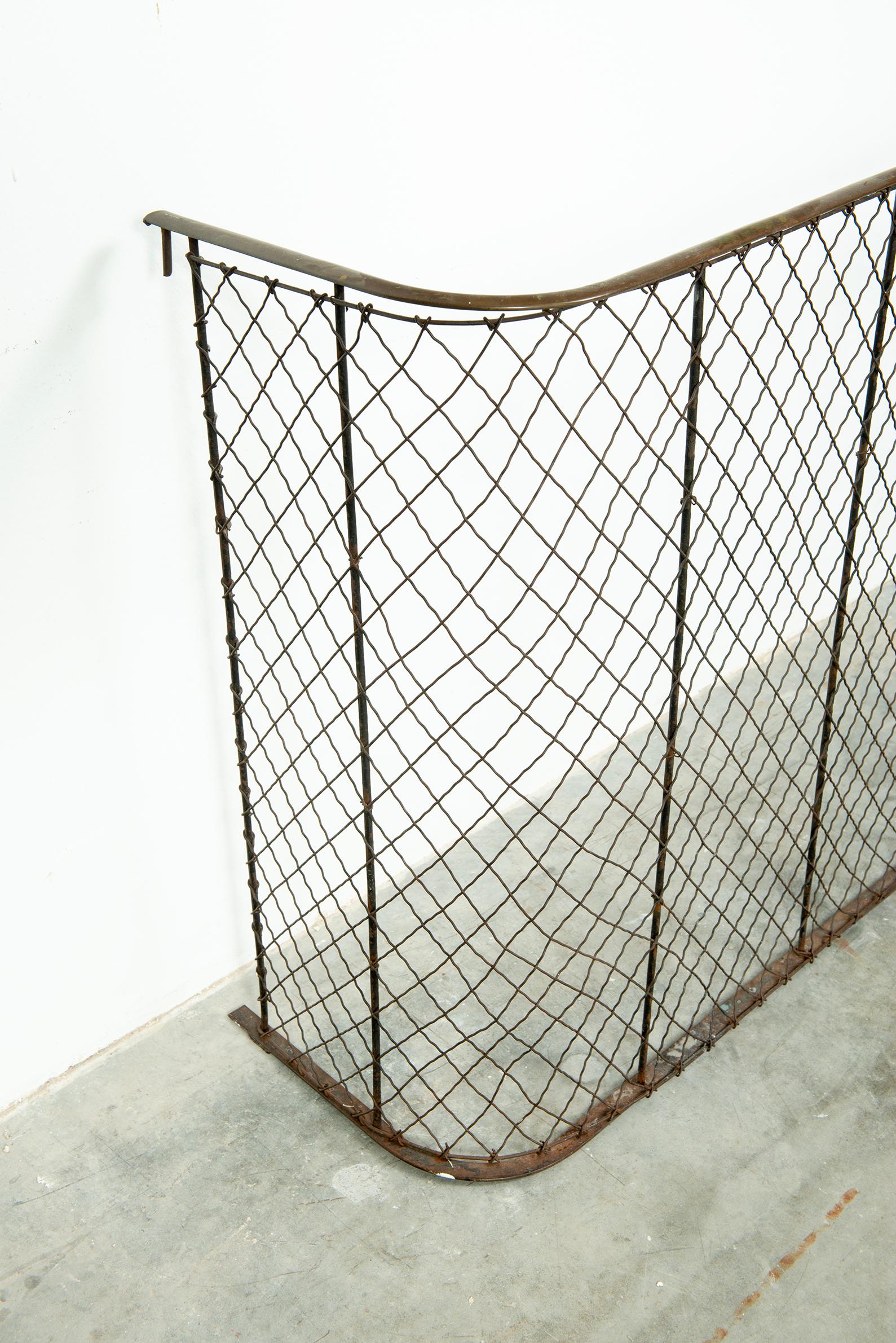 A fireplace screen with diagonal wide mesh on nine vertical iron supports and with an iron base rail and a brass top rail. 
This one is 50 inches long. Designed not as a spark guard but as a functional piece to keep children and dogs away from the
