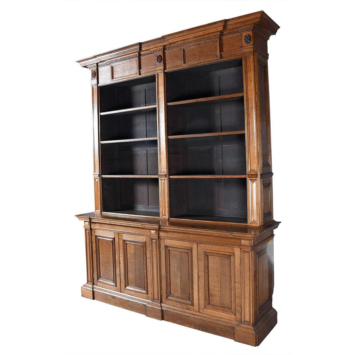 Una libreria in Oak di dimensioni massicce e di grande interesse architettonico. Il forte cornicione sporgente è ornato da modanature a dentello e rosette intagliate. Gli sportelli inferiori dell'armadio e i lati della cassa sono rivestiti di