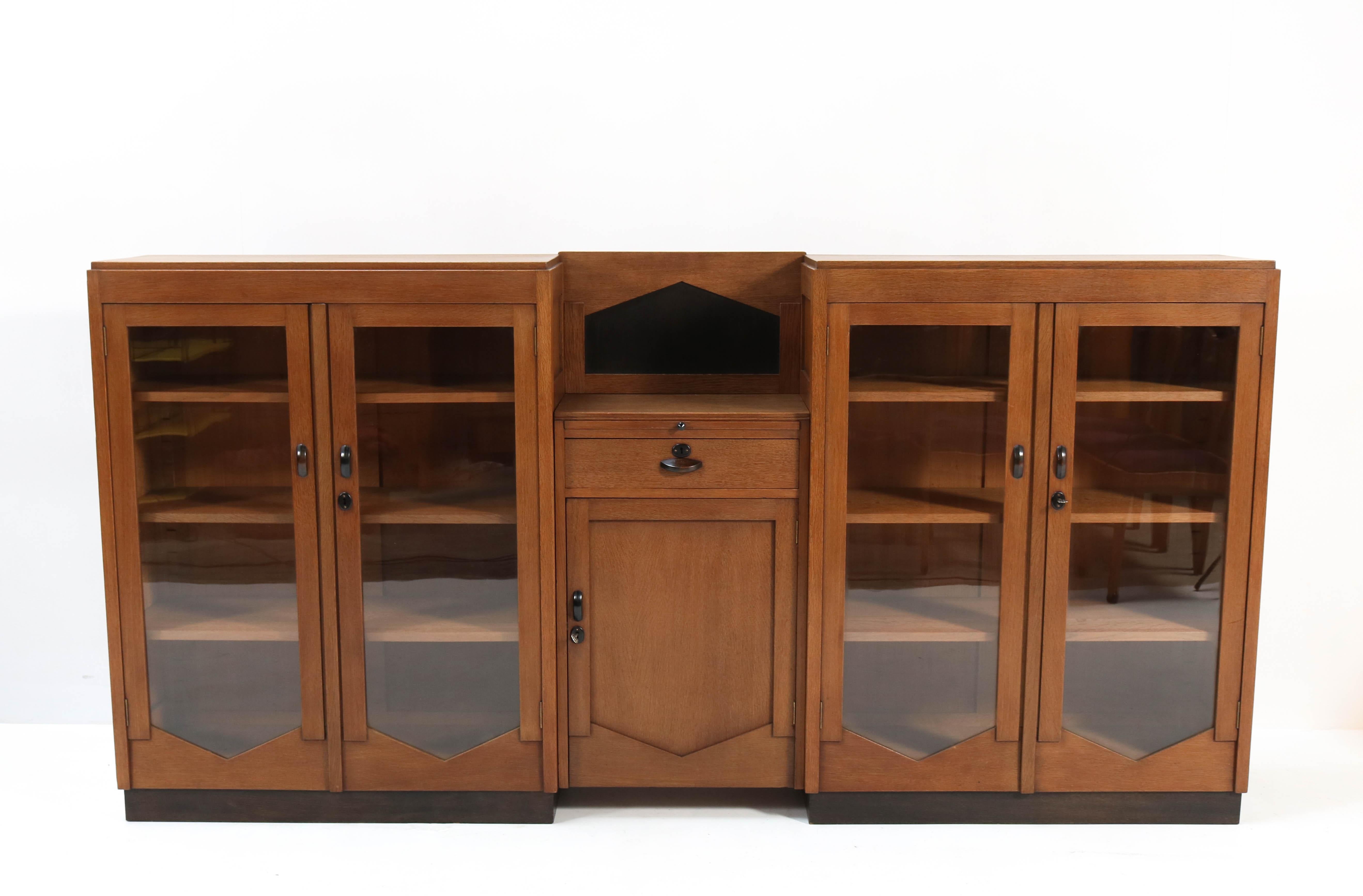 Magnificent and rare Art Deco Amsterdam School large bookcase.
Striking Dutch design from the 1920s.
Solid oak with original glass in the doors.
Original black lacquered handles.
Eight original solid oak shelves adjustable in height.
This