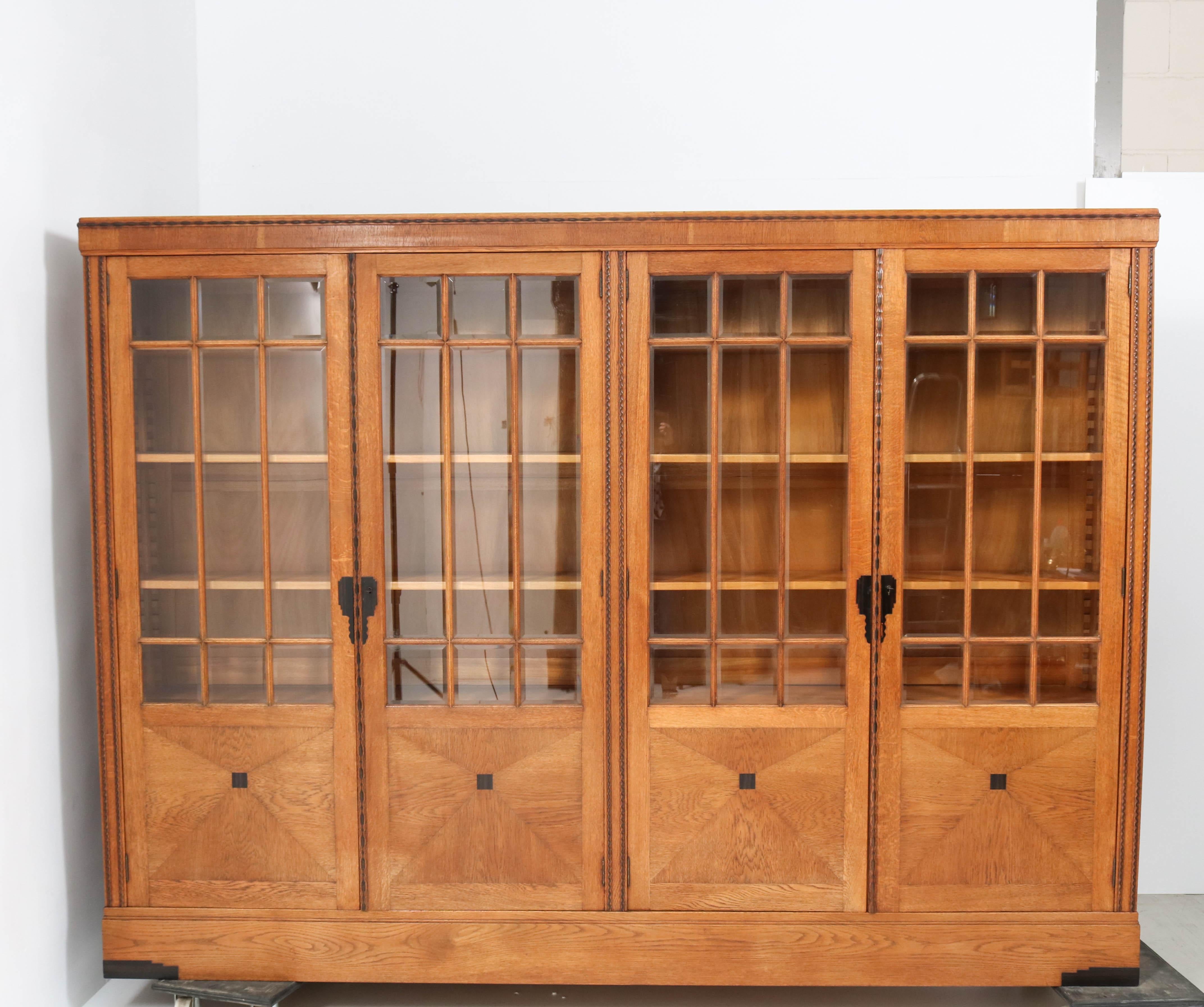 Magnificent and rare Art Deco Amsterdamse School library bookcase.
Striking Dutch design from the 1920s.
Solid oak and original oak veneer with macassar ebony lining.
Each of the four doors has nine original beveled glass pieces.
Ten original