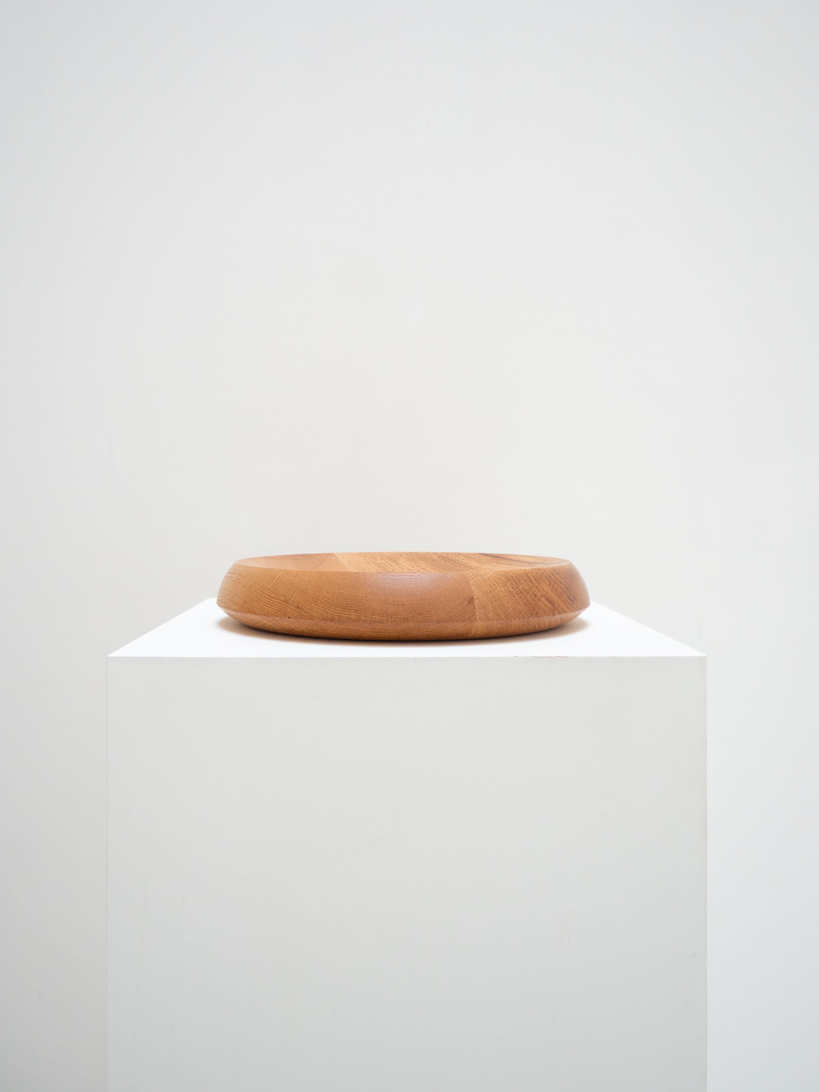 Designed by Peter de Jong, this large oak bowl captivates with its precise lines. The oak grain is accentuated by an opening at the bottom of the bowl, adding a subtle and unexpected graphic detail.