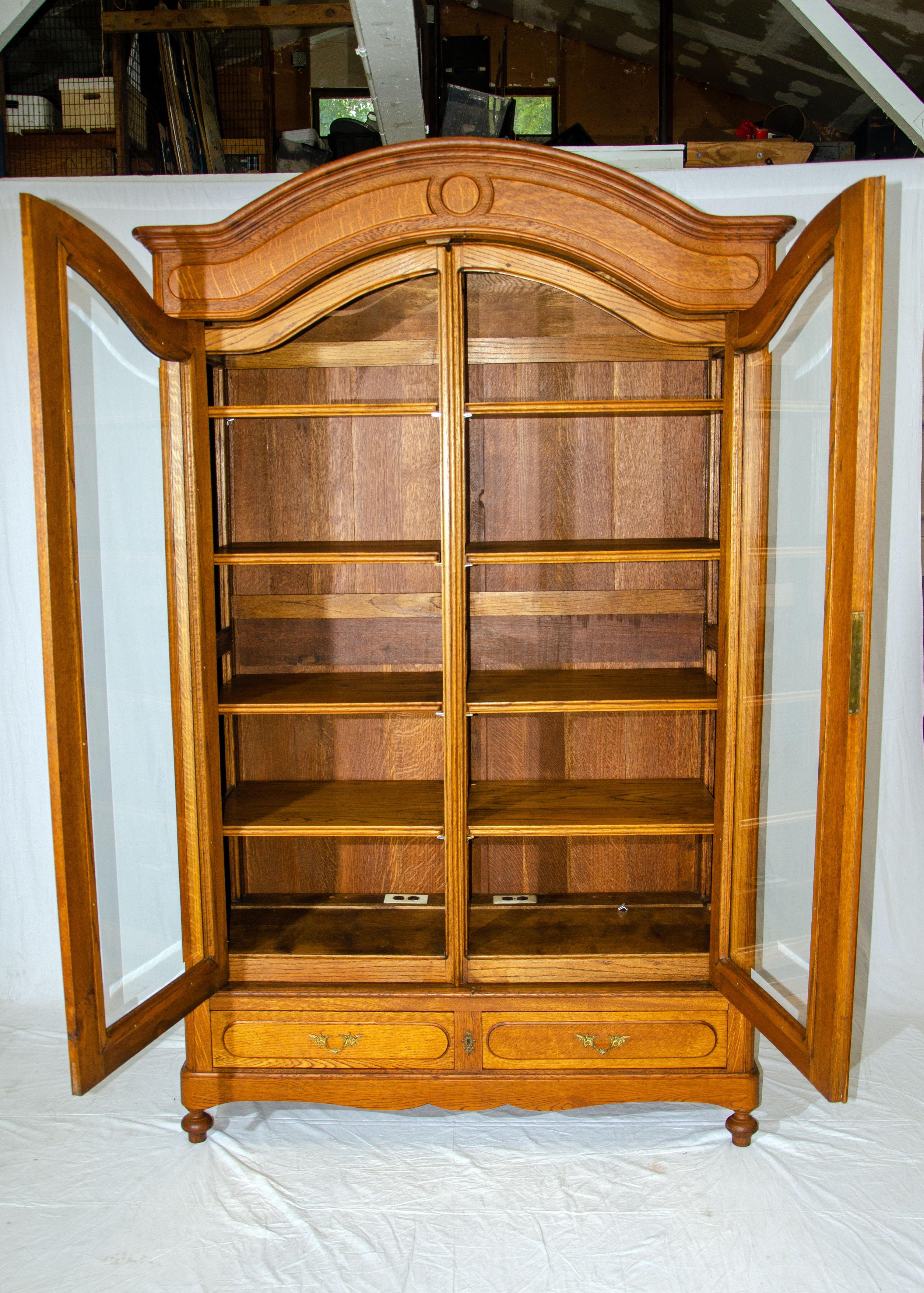This beautiful large oak cabinet has clear beveled glass doors, adjustable shelves, and two storage drawers in the base. The previous owner used this piece as a stereo cabinet as it is deep enough for all components. This cabinet can also be used