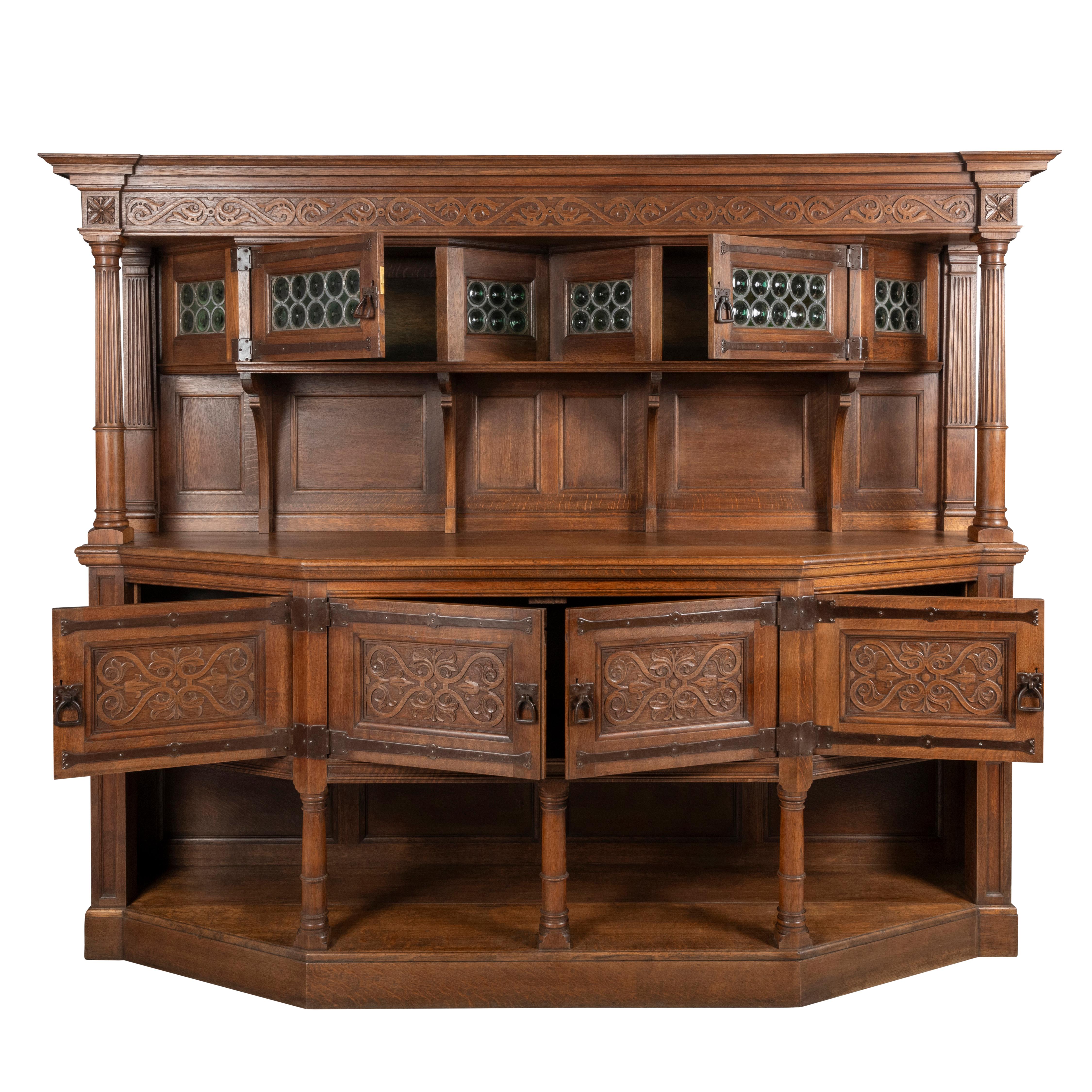A large Liberty Oak Dresser.

The breakfront cornice set with a band of carved stylized carving in bas relief.

The upper structure set with 2 leaded glazed cupboards, above a shelf and in between a pair of reeded columns.

The lower section with 4