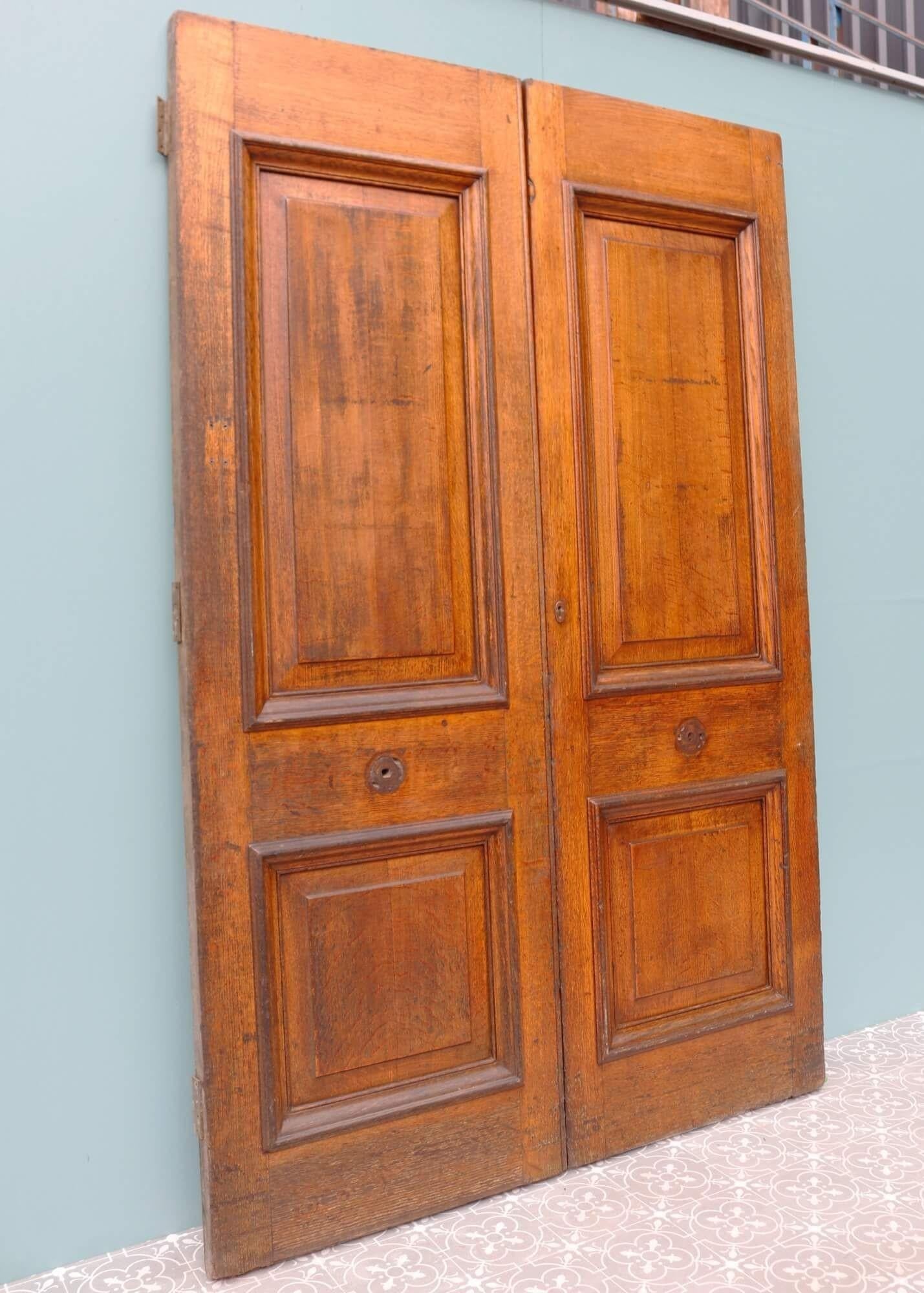 This handsome pair of large antique double front doors set the stage as an impressive entrance to an Edwardian or Victorian townhouse. Dating from the early 20th century, these double doors have a warm and inviting colour that showcases the unique