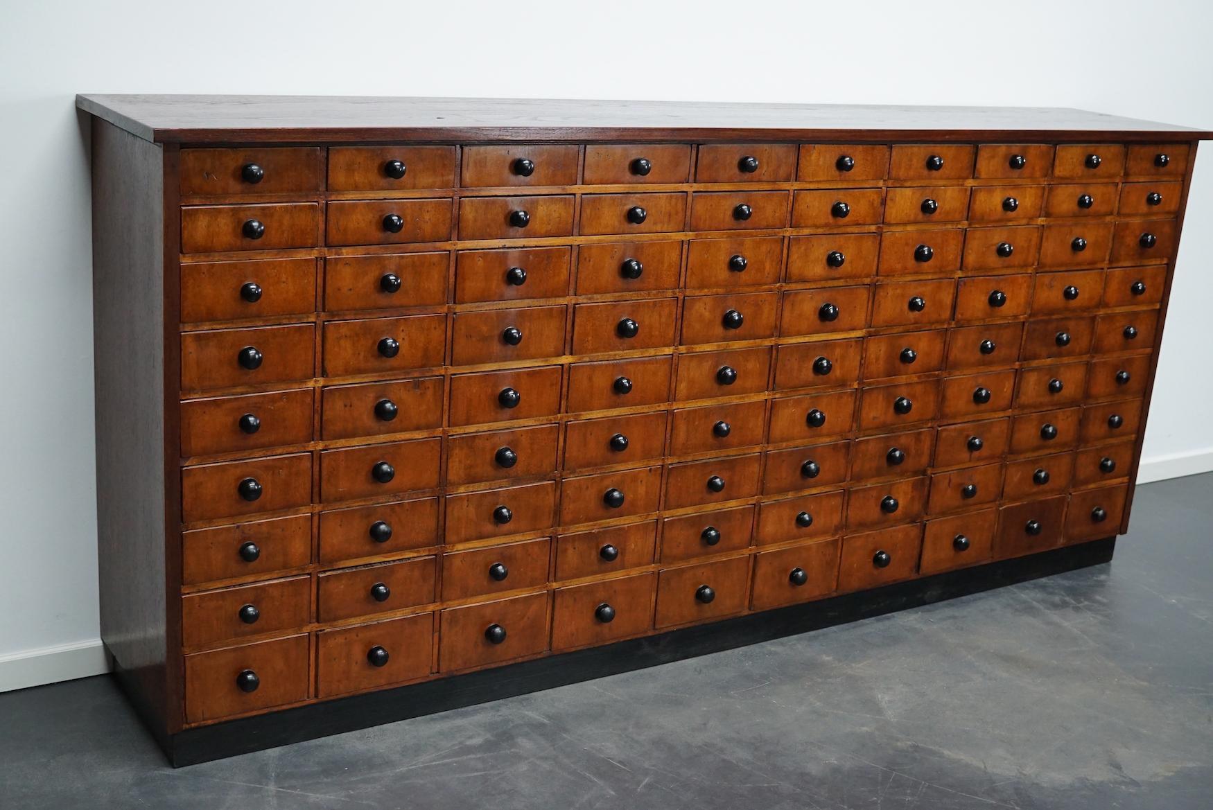 This apothecary cabinet was made circa 1950s in Germany. It features 90 drawers with black knobs. The interior dimensions of the drawers are: D x W x H 36.5 x 19 x 6, 7.5 and 11 cm, some of the drawers have dividers and some don't.
Details.
 