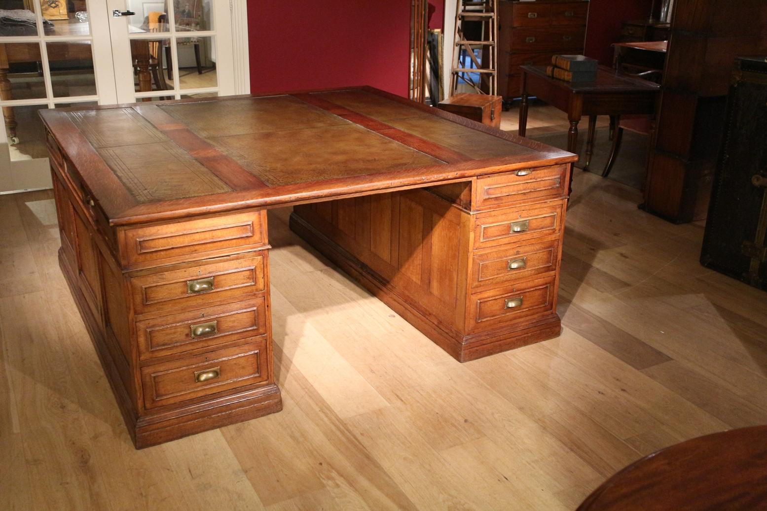 Large antique oak partners desk in very good condition. Nice warm color and green leather. The desk has a special configuration. It has 6 drawers on both sides. In addition, on both sides a cupboard and 4 pull-out baths in total. The desk has a lot