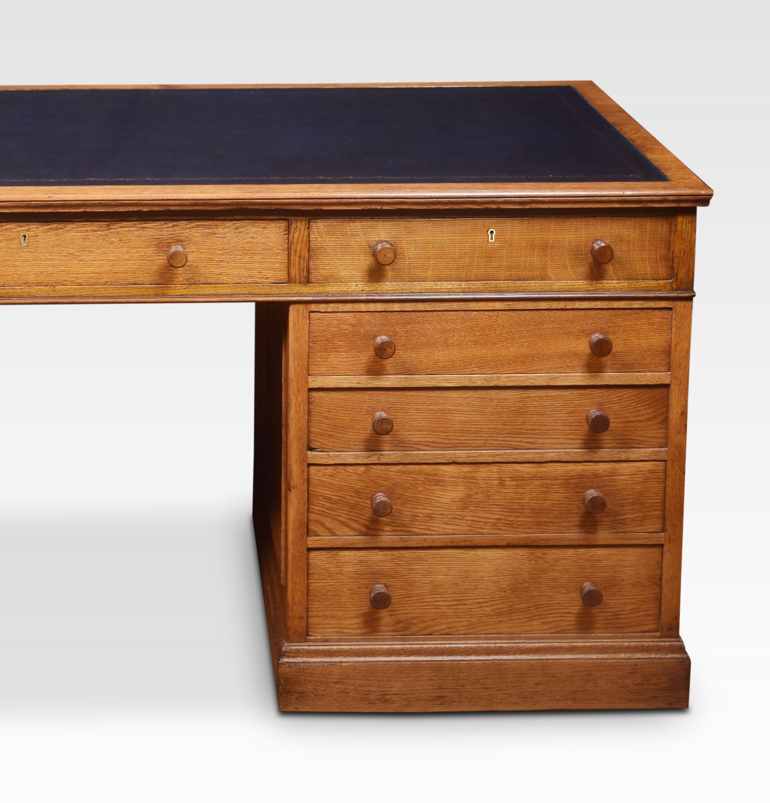 Large oak pedestal desk the rectangular top with inset leather having tooled border enclosed by a molded edge over an arrangement of three freeze drawers. Above two large pedestals, one side with two banks of four drawers the opposing side fitted