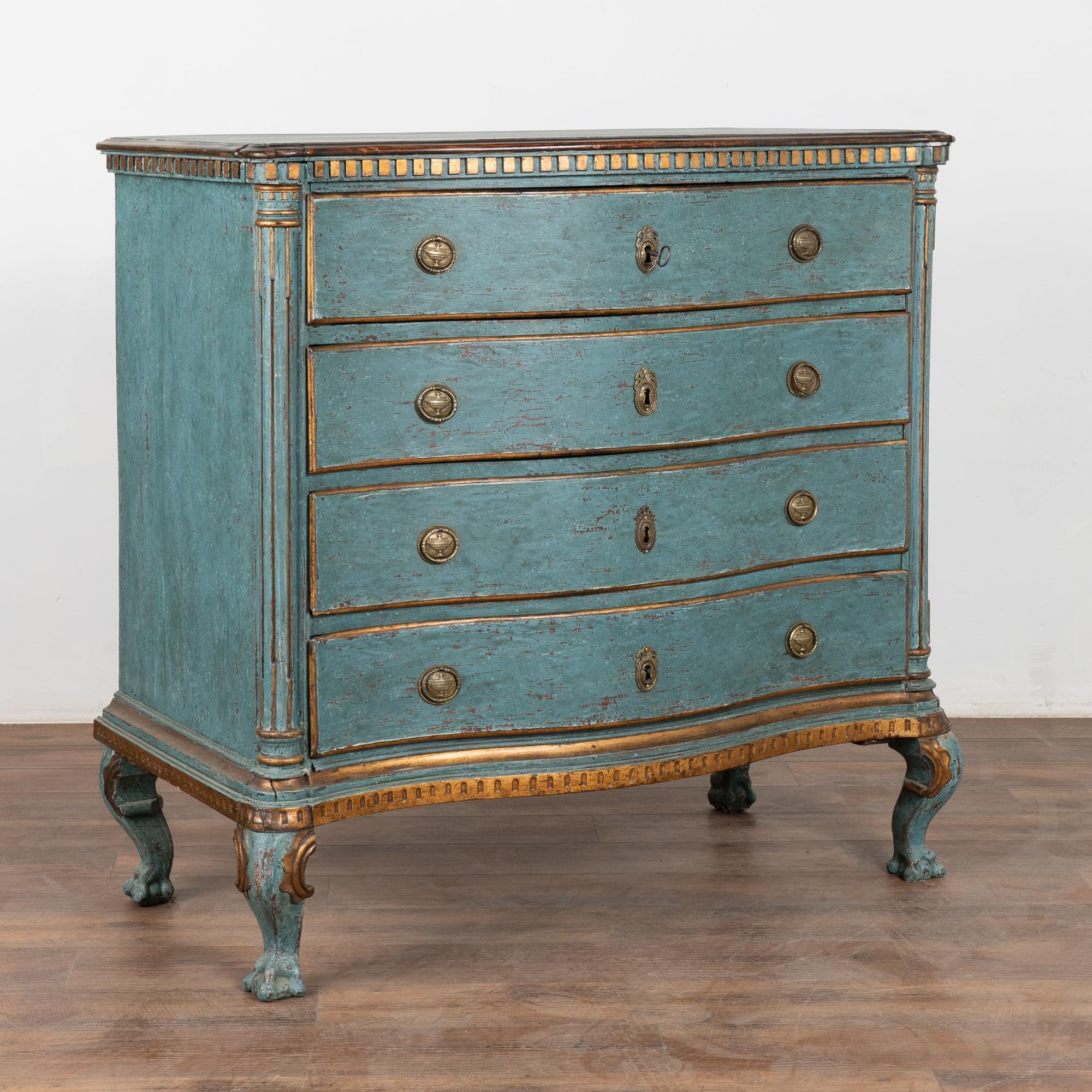 This striking rococo large oak chest of four drawers features a serpentine front, dentil molding, brass hardware pulls and is raised on large cabriolet feet.
Later professionally painted in layered shades of blue with burnished bronze accents, all