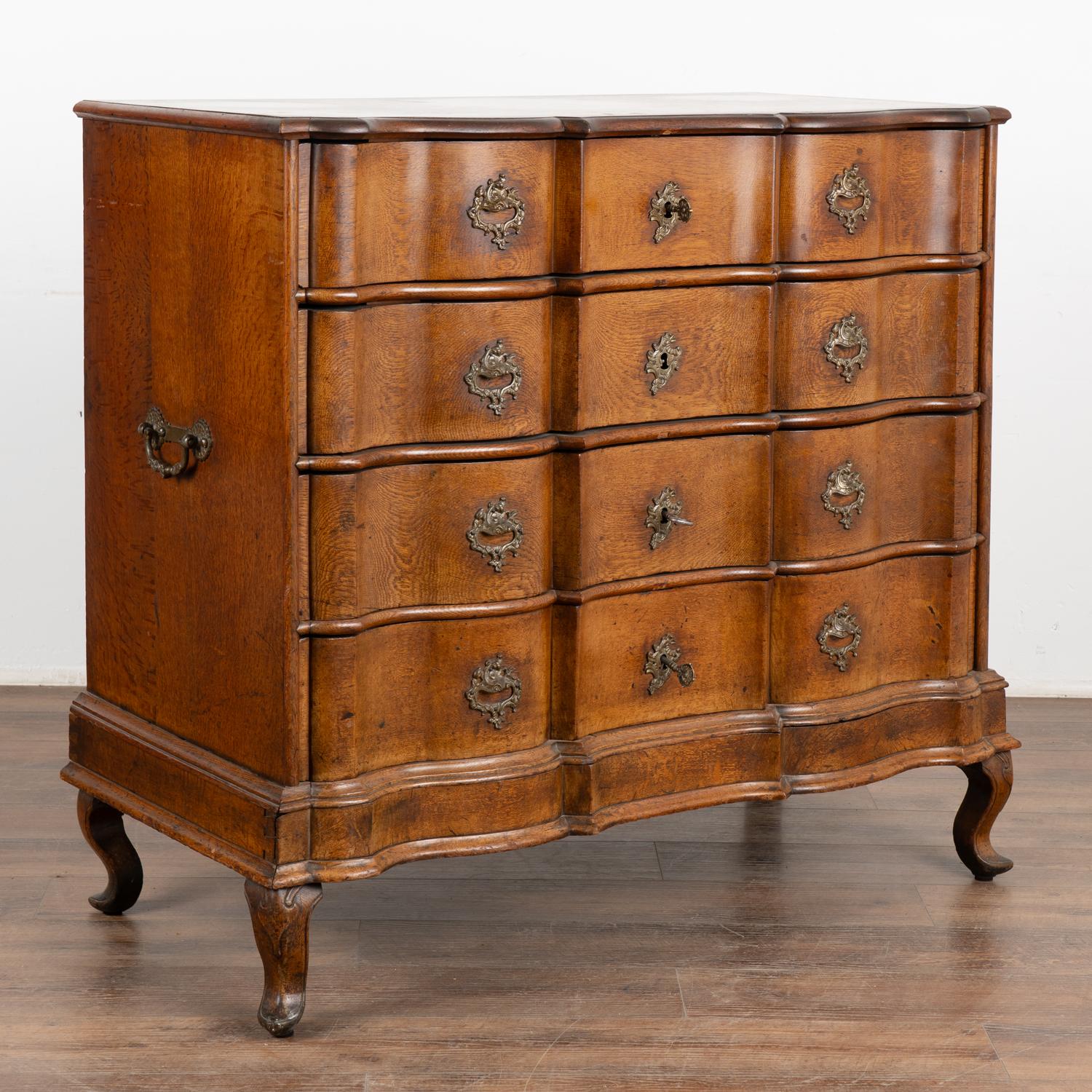 This large antique rococo oak chest of drawers features a serpentine front, handsome brass hardware pulls and rests on cabriolet feet.
This chest has been restored, case is sturdy and drawers function. Key is used in each of the five drawers in