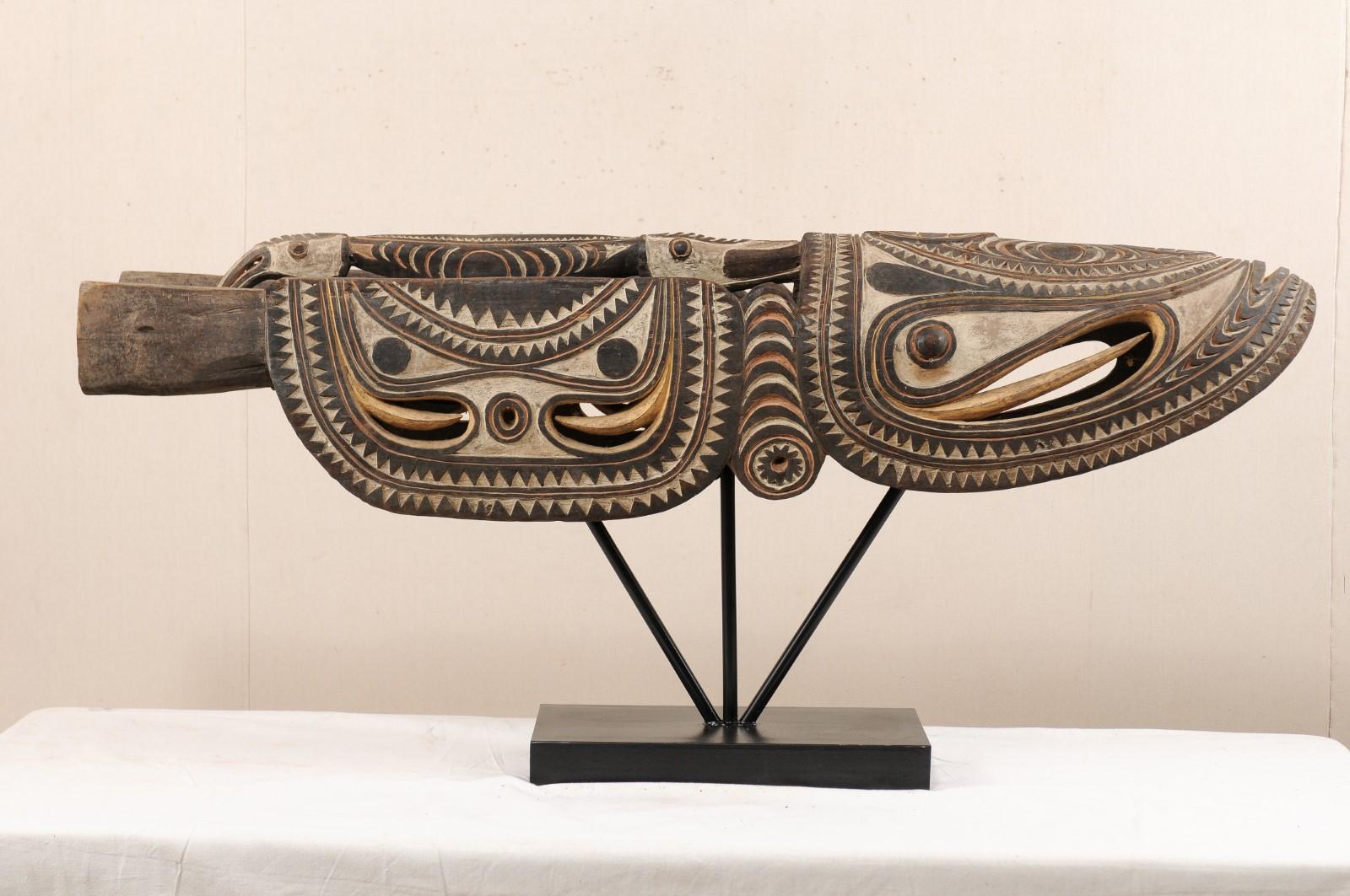 A large-sized Papua New Guinea carved canoe prow from the Upper Sepik River region on custom stand. This vintage boat prow from Papua New Guinea has been carved out of wood and features a stylized crocodile motif with elaborate pigmentation which