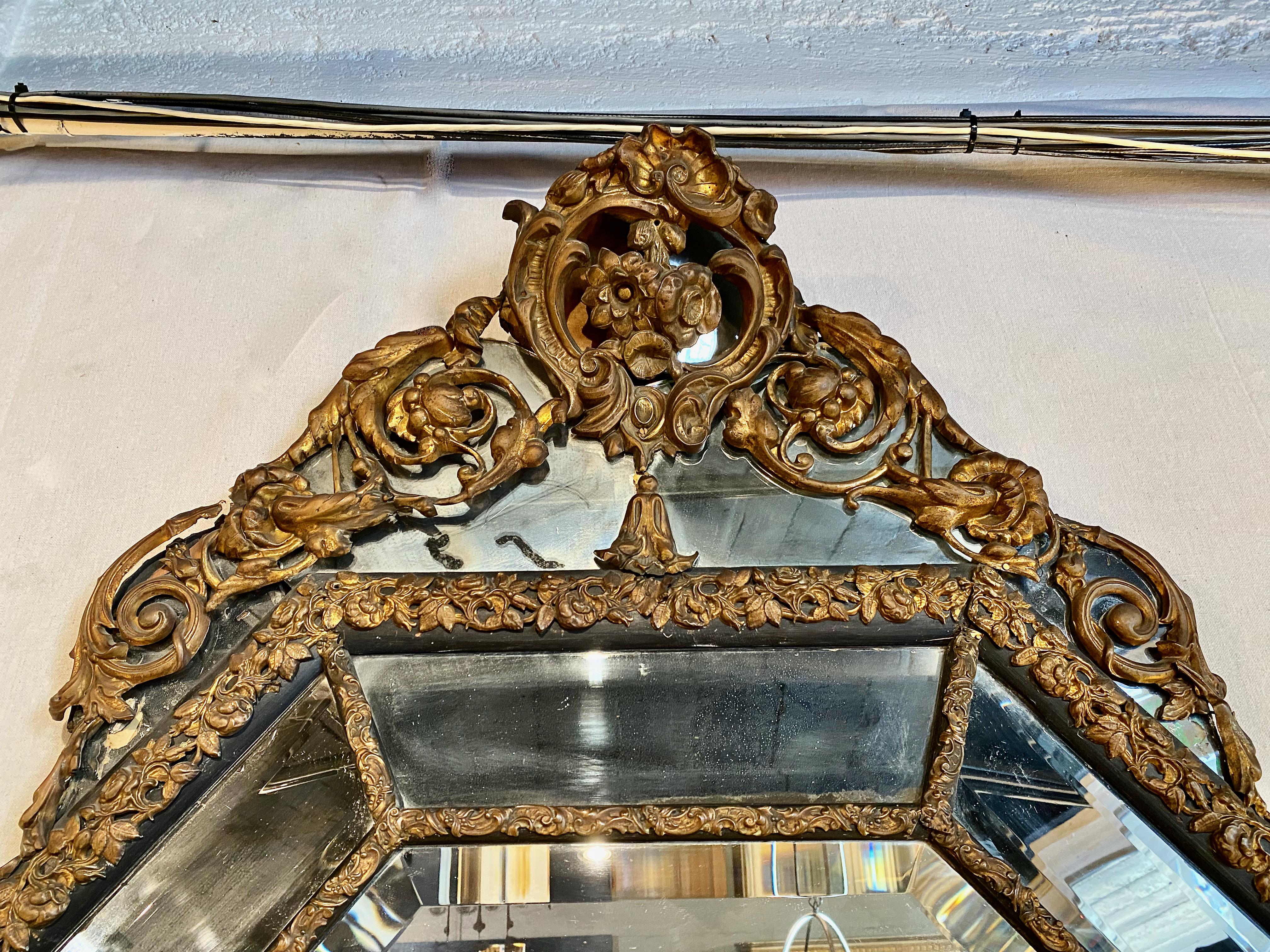 This is a very large octagonal cushion-form repousse brass mirror. The size alone makes this mirror unusual, when combined with the fact that the form is cushioned and octagonal, the mirror becomes spectacular. The mirrored sections are beveled