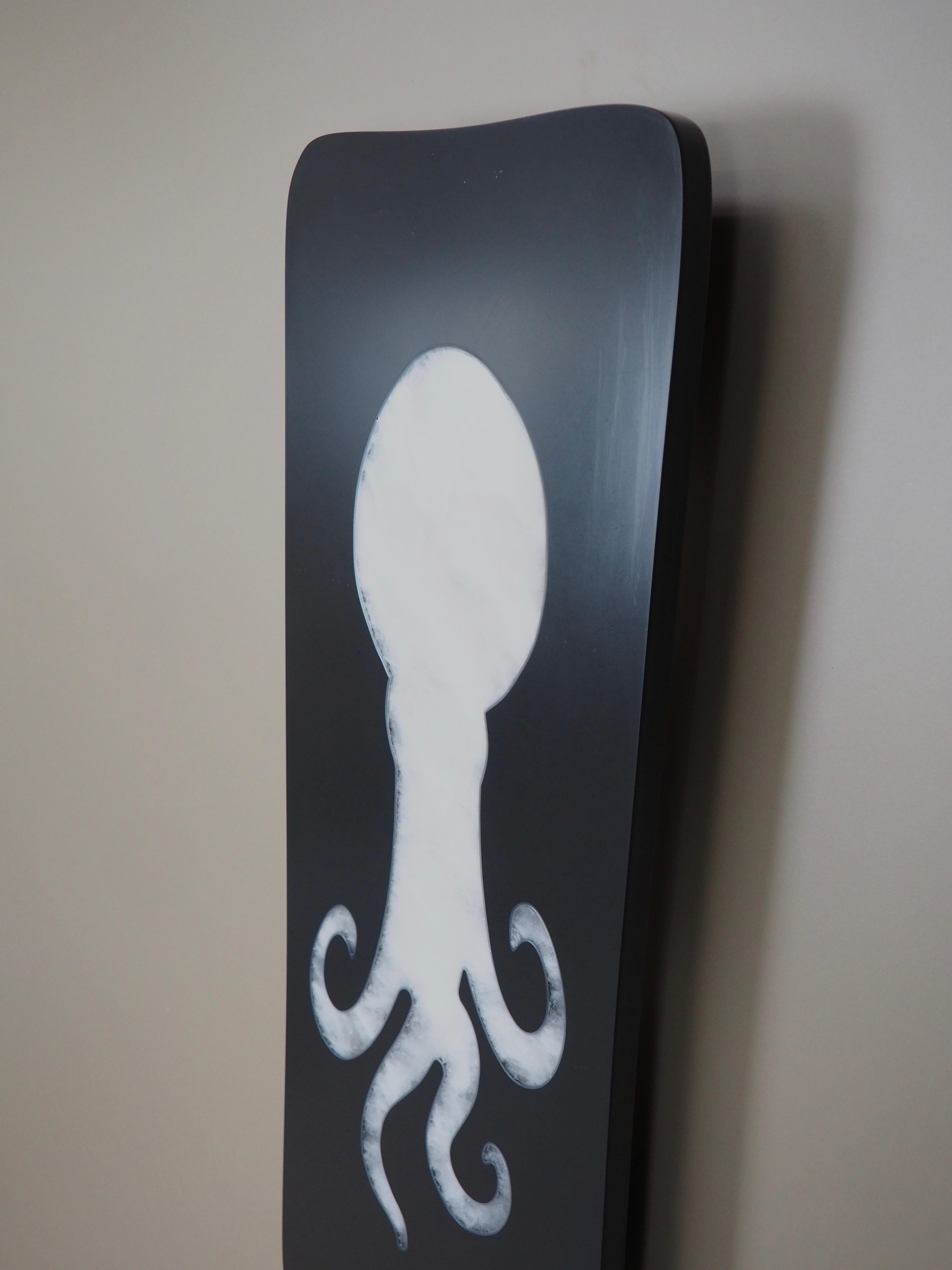 Esta gran lámpara de pared está hecha de una losa de pizarra pulida de 2 cm de grosor con una inclusión de cristal de roca en forma de pulpo estilizado.

La iluminación corre a cargo de dos grandes bombillas E27/E26 de 30 cm protegidas por un