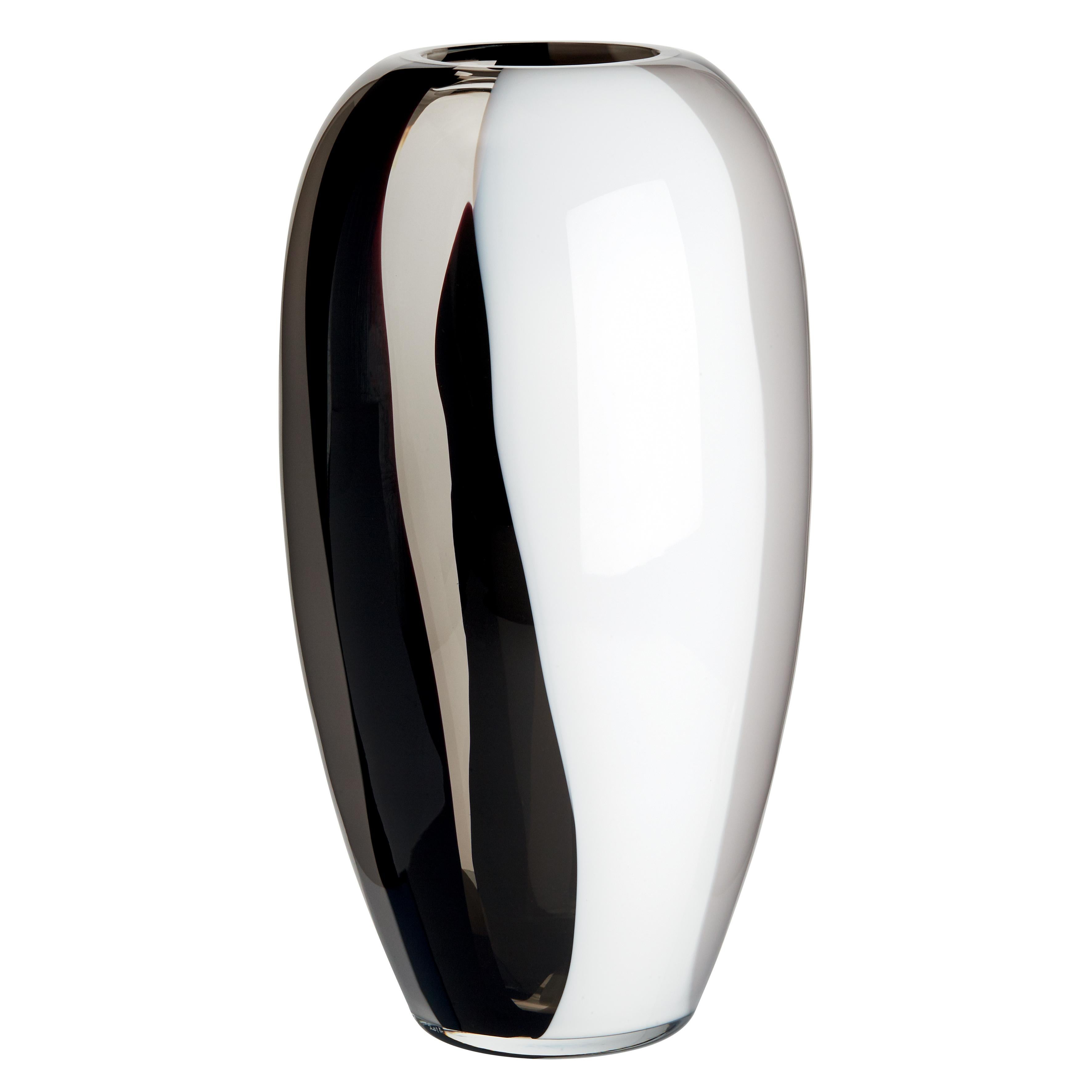 Die Eleganz der Einfachheit. Ogiva ist eine achsensymmetrische, schlanke Vase, die aus jedem Blickwinkel ins Auge fällt. Die Version, die die Transparenz des Stahlkristalls mit den undurchsichtigen Farben Milchweiß, Grau und Schwarz verbindet, ist