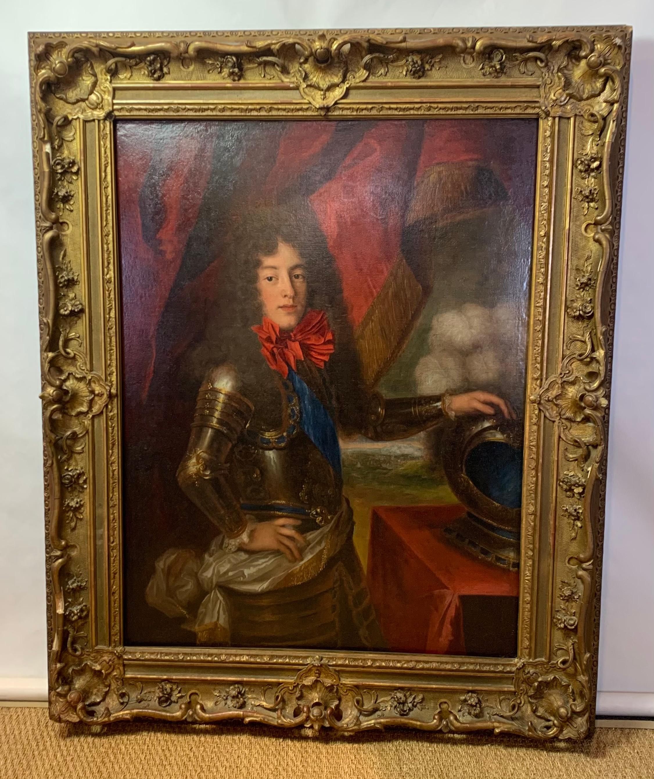 A large 18th century oil on canvas painting of Louis, Prince of Condé, dressed in full battle armor in an elaborately carved gilt wood frame.
