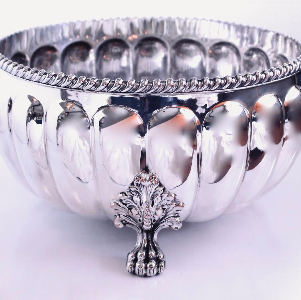 A magnificent antique English silver bowl with a boldly reeded body and gadrooned rim resting on detailed lion’s paw feet which spring from robust acanthus sprays mounted to the body of the bowl. Excellent condition, a few scratches on the very