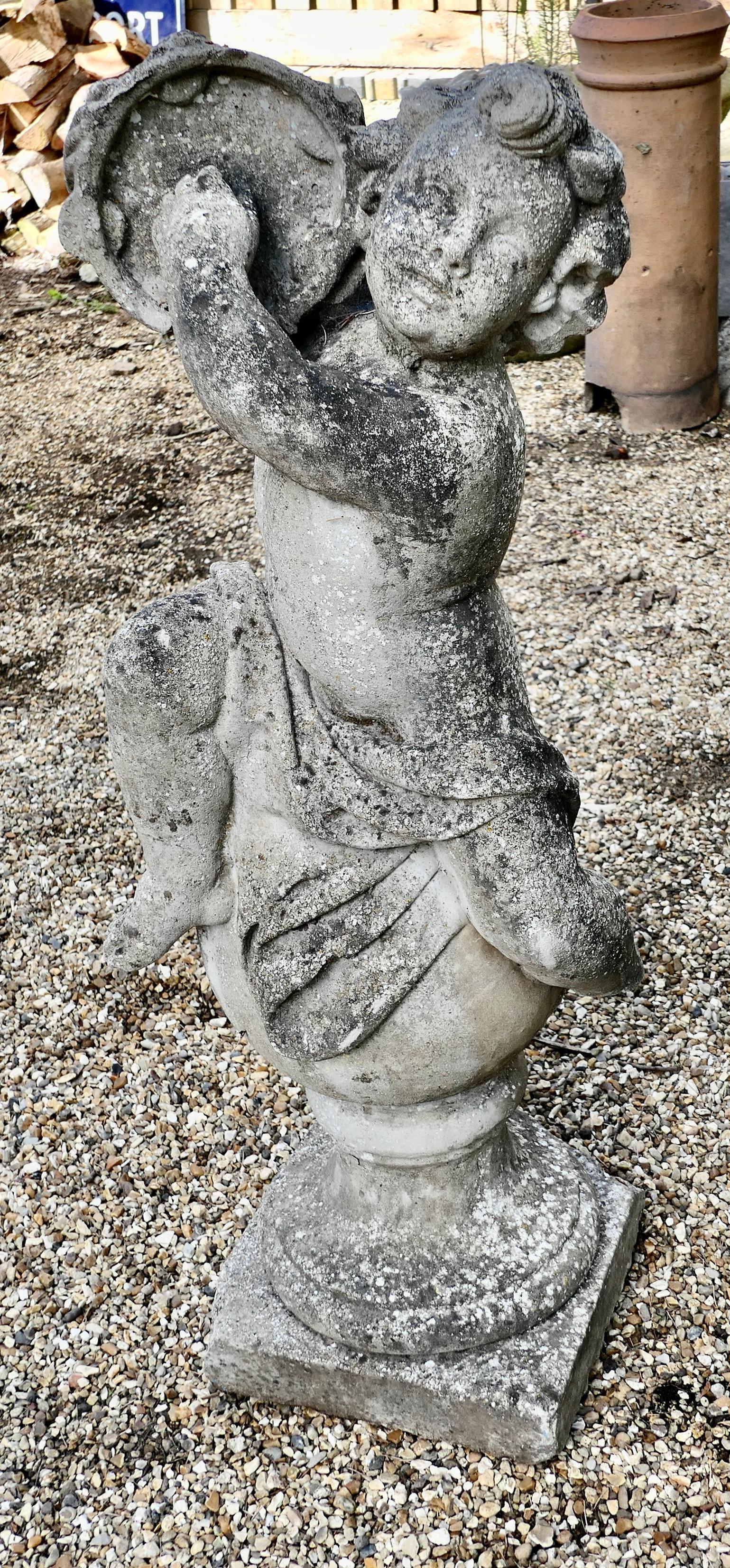 Large old weathered statue of a putti playing tambourine.

The musical nymph is sitting on a large sphere set on a square base.
This is a very weathered piece in good detail to be viewed from all sides, his foot at the back has a piece
